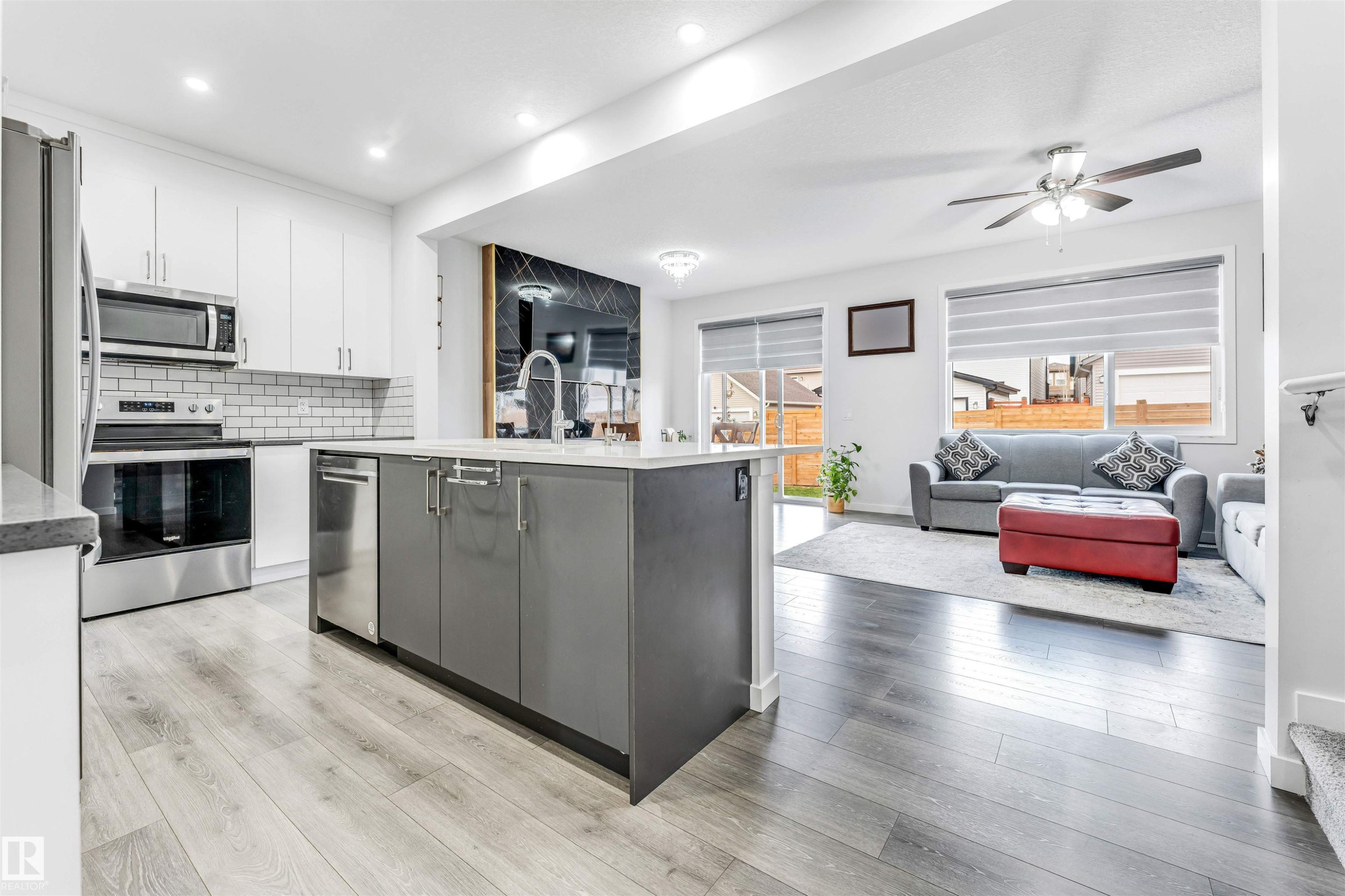 Modern kitchen featuring stainless steel appliances, white subway tile backsplash, a center island with a sink, and wood-finish flooring - 425 41 Street, Edmonton, AB - Indoor Photo Showing Kitchen With Stainless Steel Kitchen