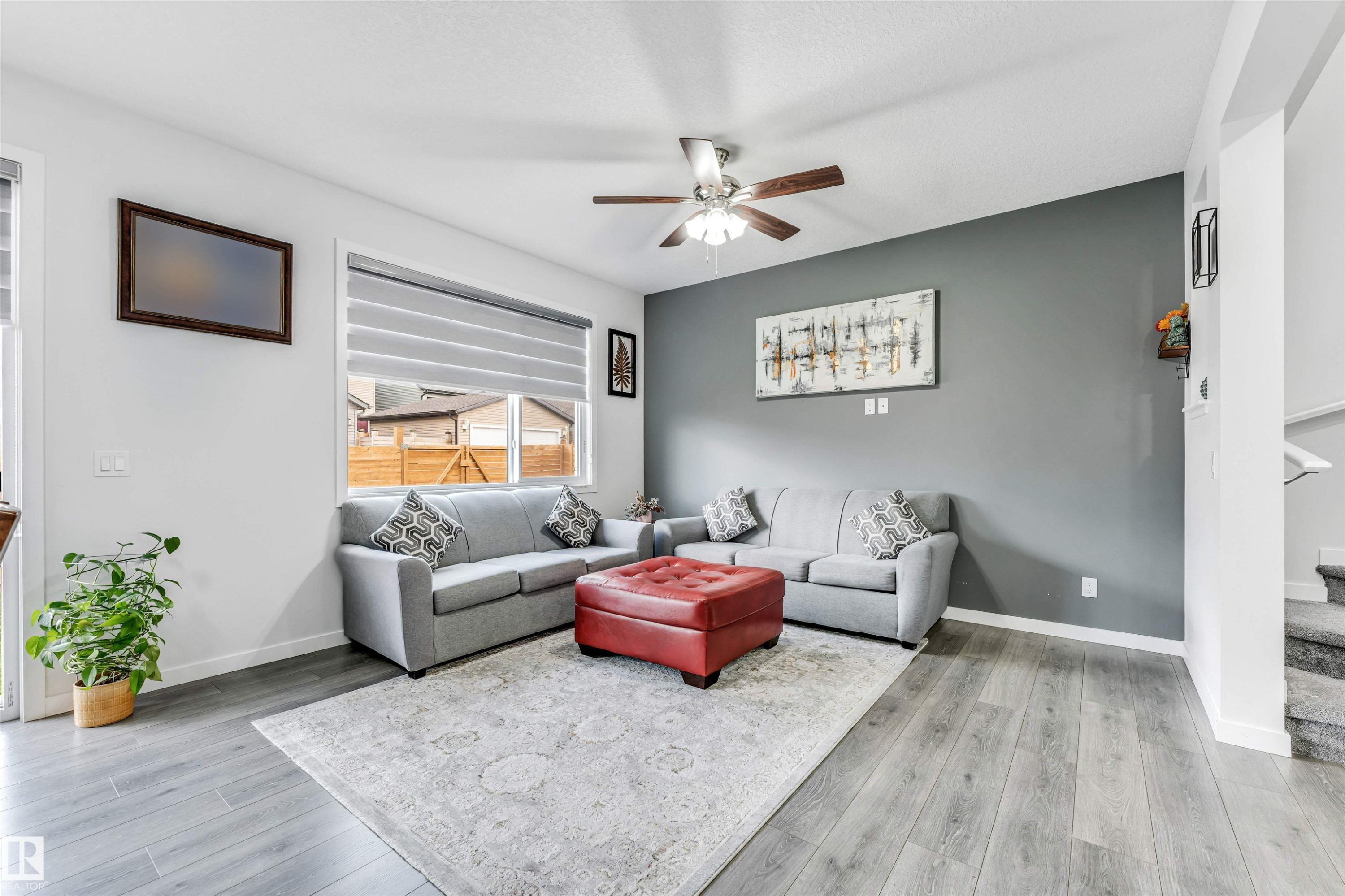 Spacious living area featuring wood-finish flooring, a contemporary ceiling fan, and a prominent accent wall - 425 41 Street, Edmonton, AB - Indoor Photo Showing Living Room