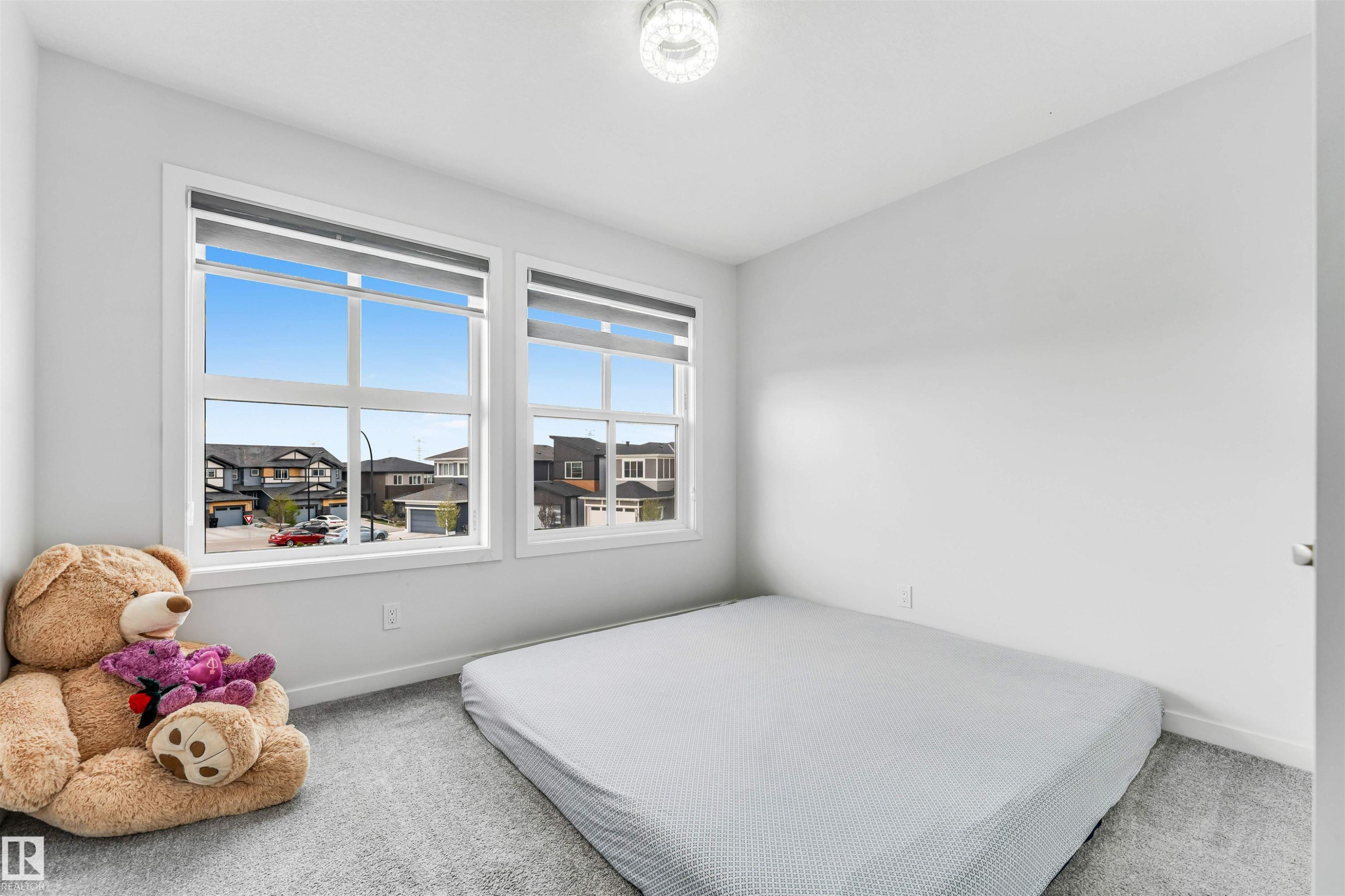 Bright room featuring two windows with white trim, light gray wall-to-wall carpeting, and a flush-mount ceiling light fixture - 425 41 Street, Edmonton, AB - Indoor Photo Showing Bedroom