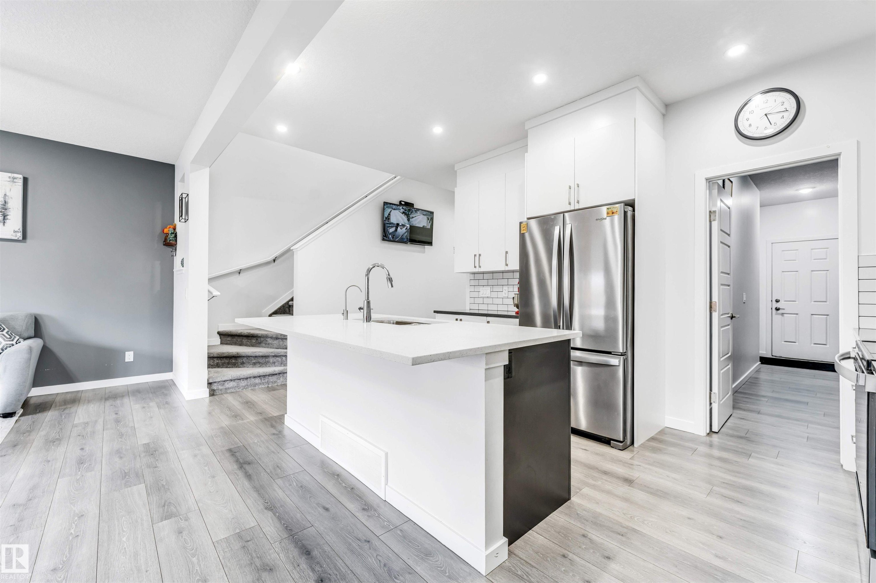 Modern kitchen featuring a central island with a sink, white cabinetry, stainless steel appliances, and a subway tile backsplash - 425 41 Street, Edmonton, AB - Indoor Photo Showing Kitchen With Stainless Steel Kitchen
