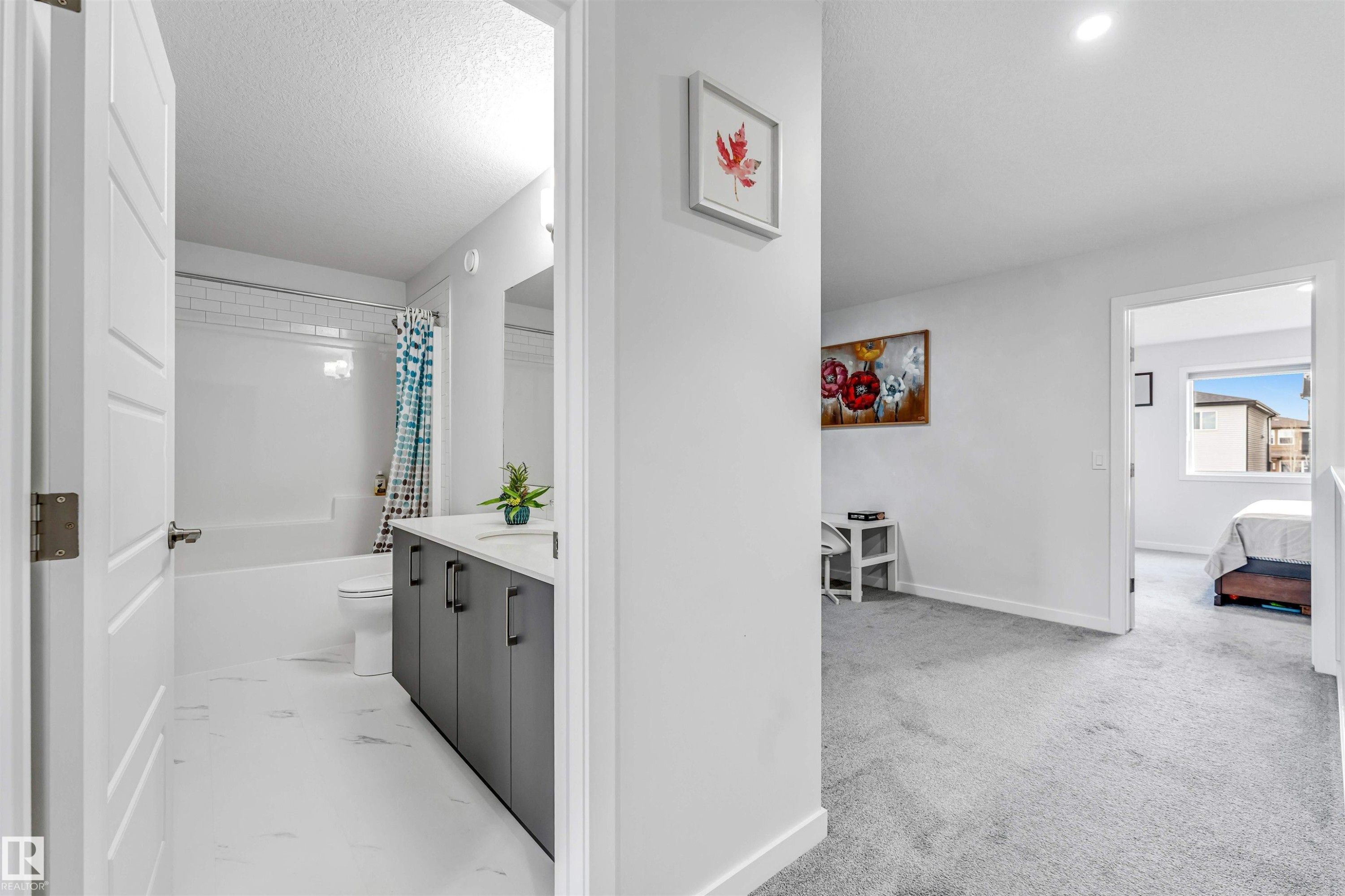 Full bathroom featuring a white subway tile surround, integrated bathtub, and a modern vanity with a white countertop and dark cabinetry - 425 41 Street, Edmonton, AB - Indoor Photo Showing Laundry Room