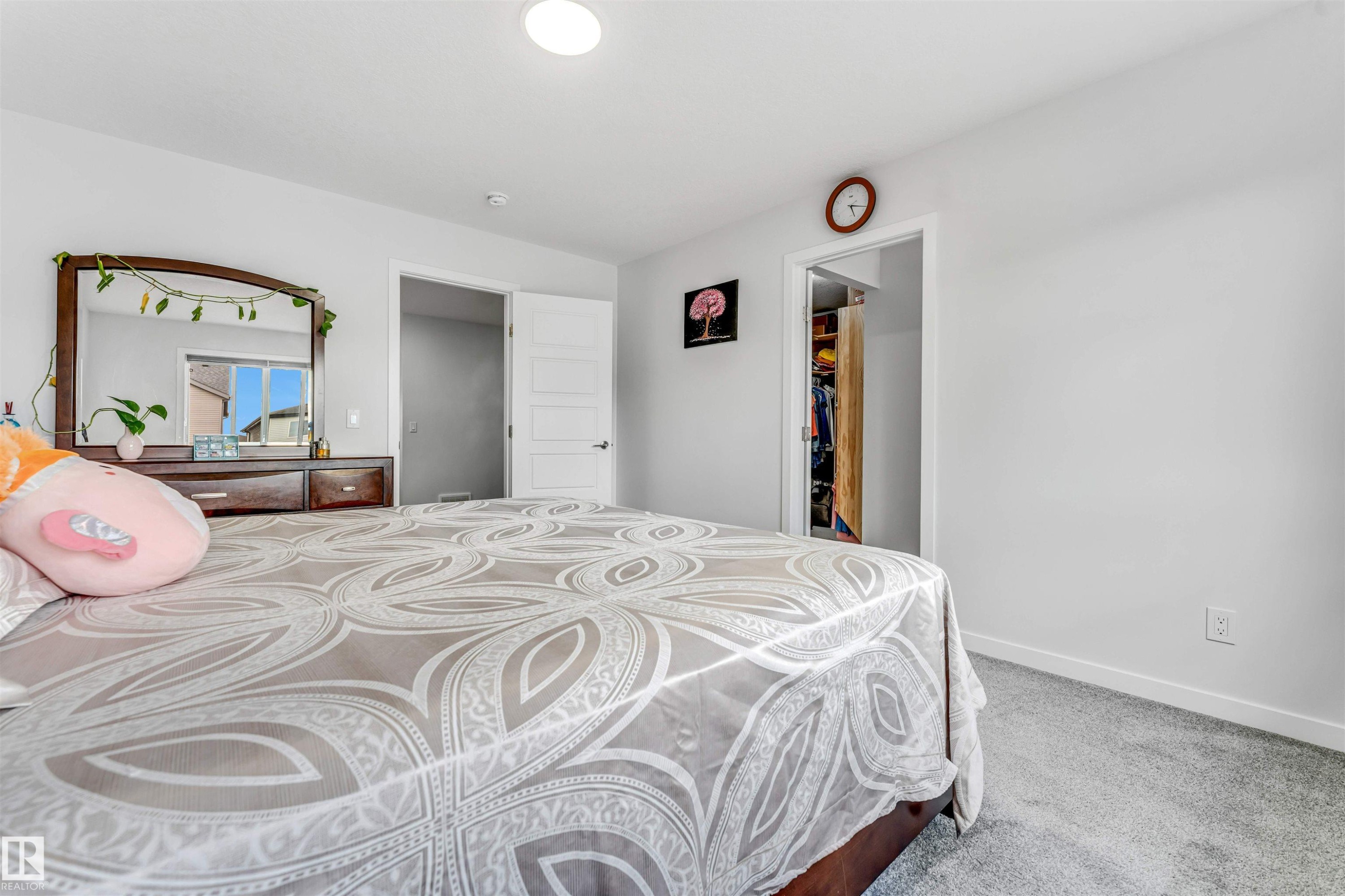 Carpeted bedroom featuring neutral wall tones, a built-in closet with an open doorway, and a second interior doorway with a five-panel door - 425 41 Street, Edmonton, AB - Indoor Photo Showing Bedroom