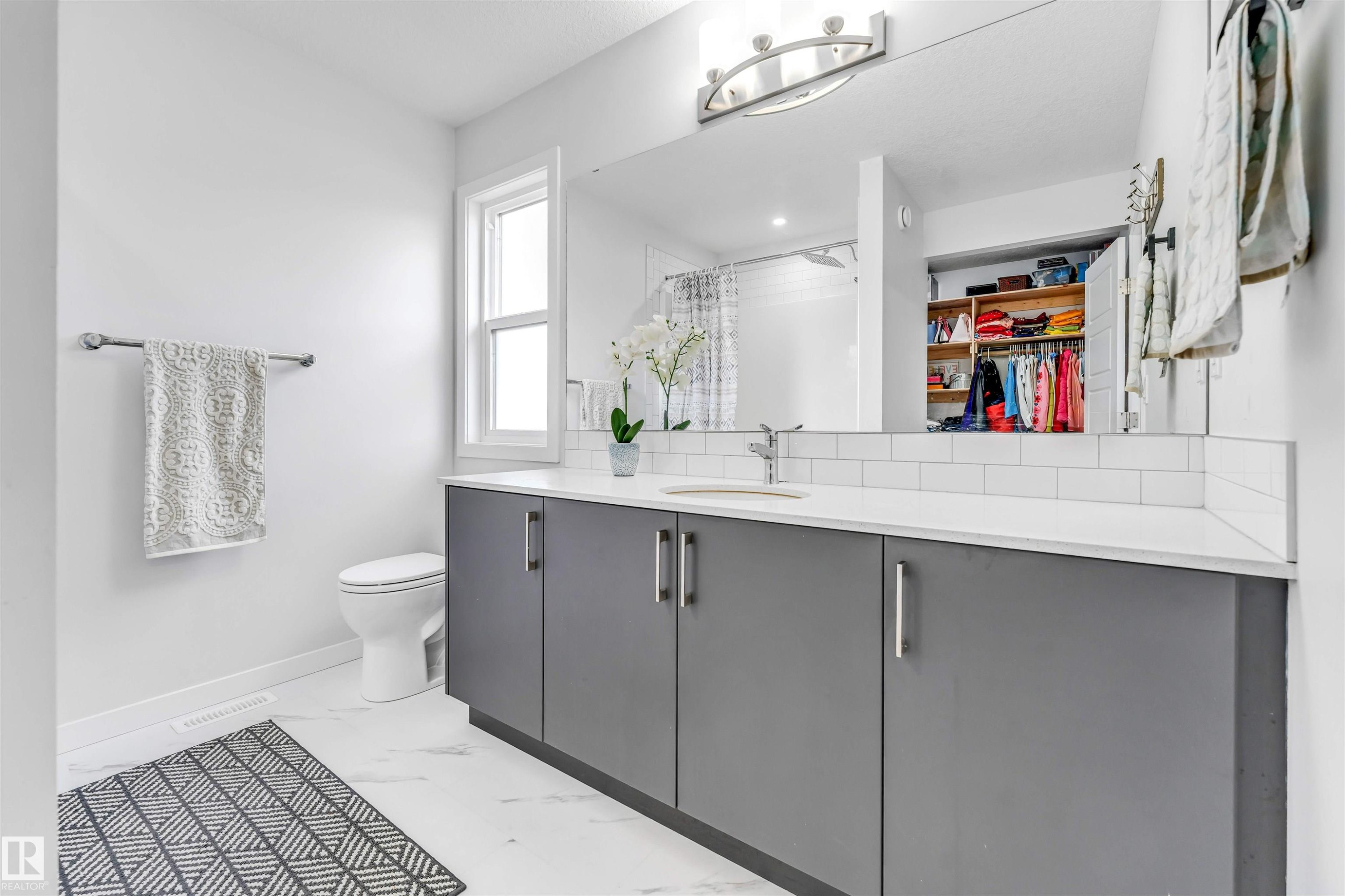 Spacious bathroom featuring a double vanity with grey cabinetry, a white countertop, and subway tile backsplash - 425 41 Street, Edmonton, AB - Indoor Photo Showing Bathroom