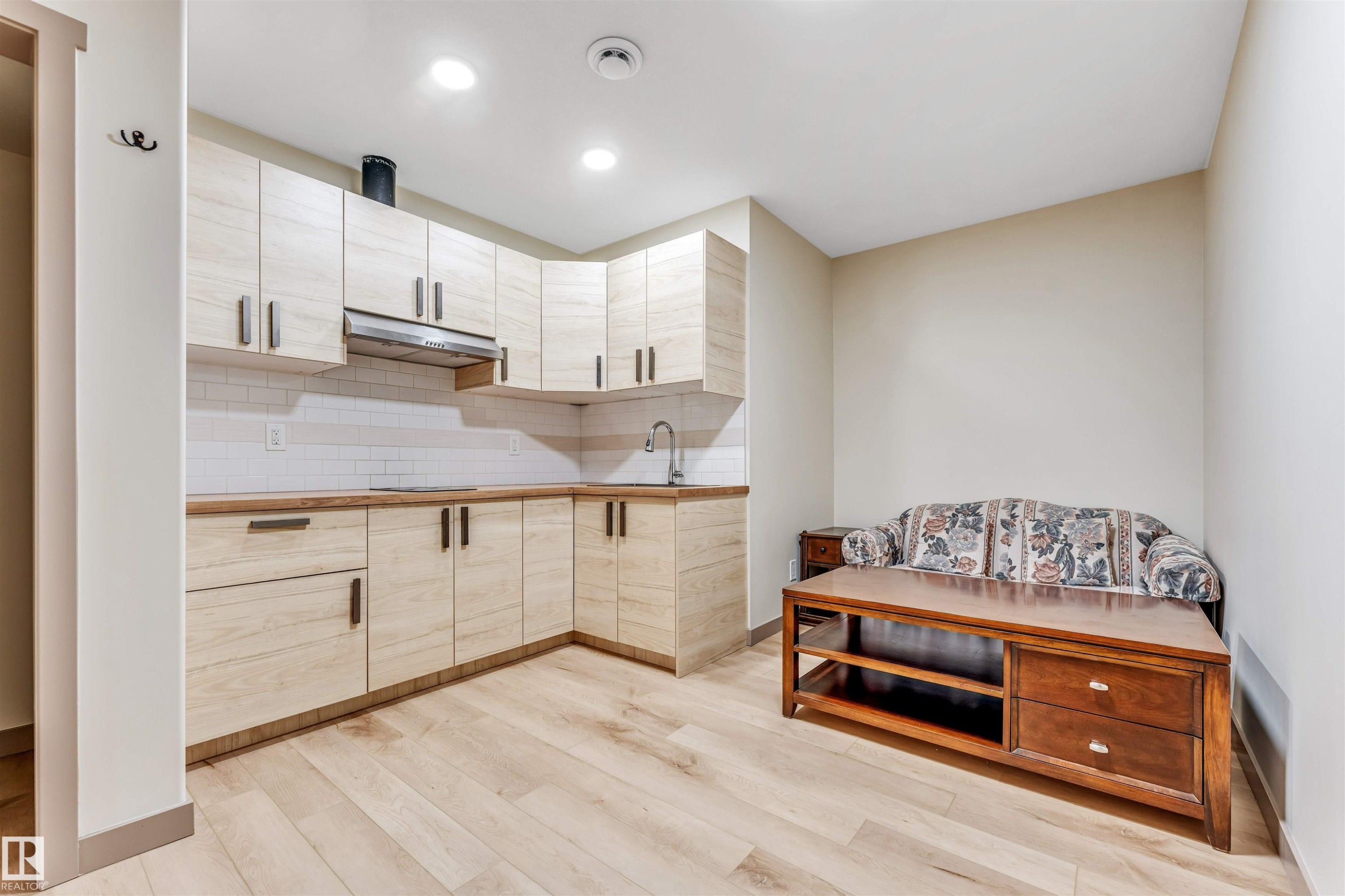 Modern kitchen area featuring light wood-finish cabinetry, a white subway tile backsplash, and light wood-finish flooring - 425 41 Street, Edmonton, AB - Indoor