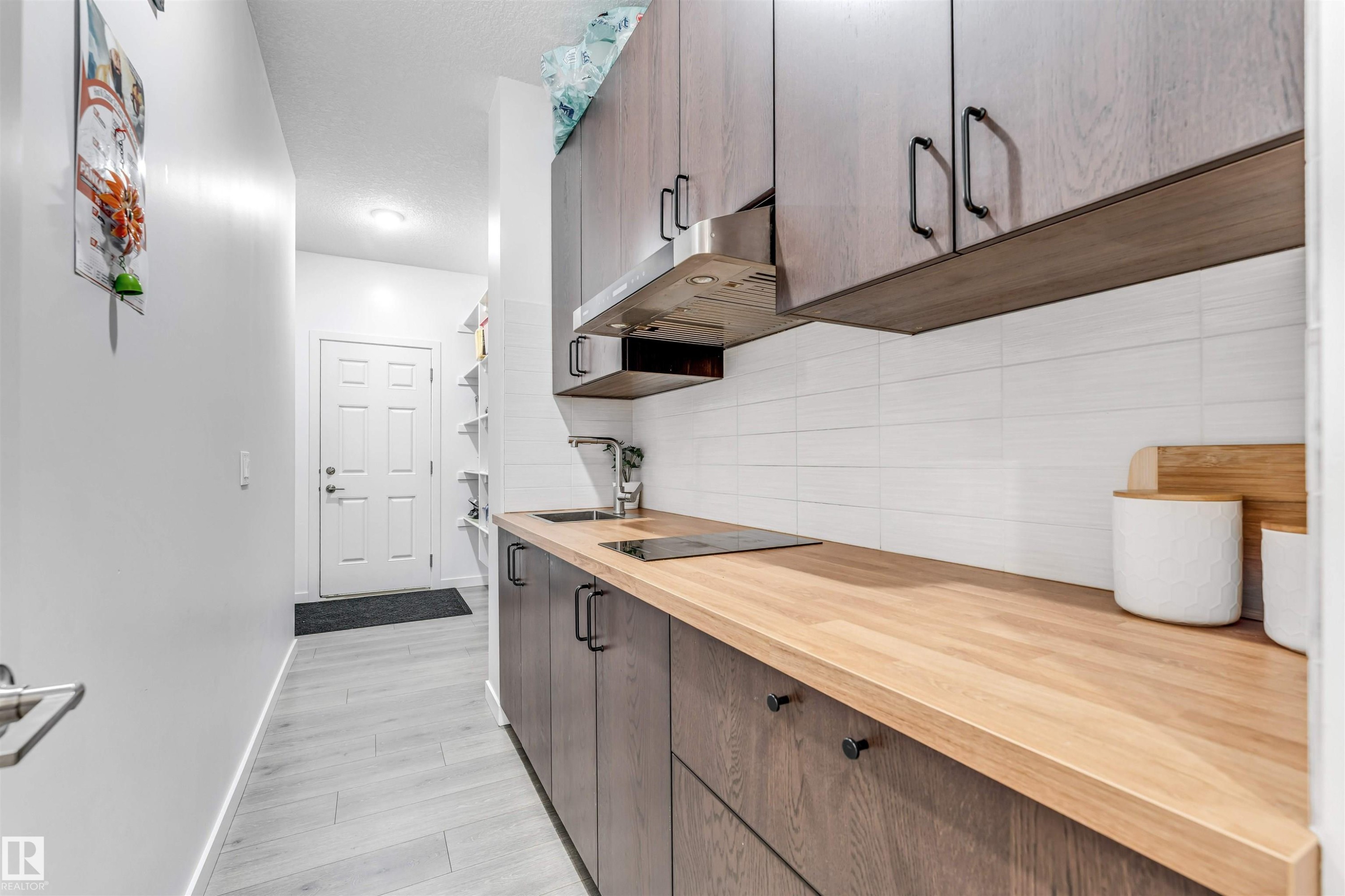 Compact kitchen area featuring wood-finish cabinetry, light wood-finish countertops, and a white subway tile backsplash - 425 41 Street, Edmonton, AB - Indoor Photo Showing Kitchen