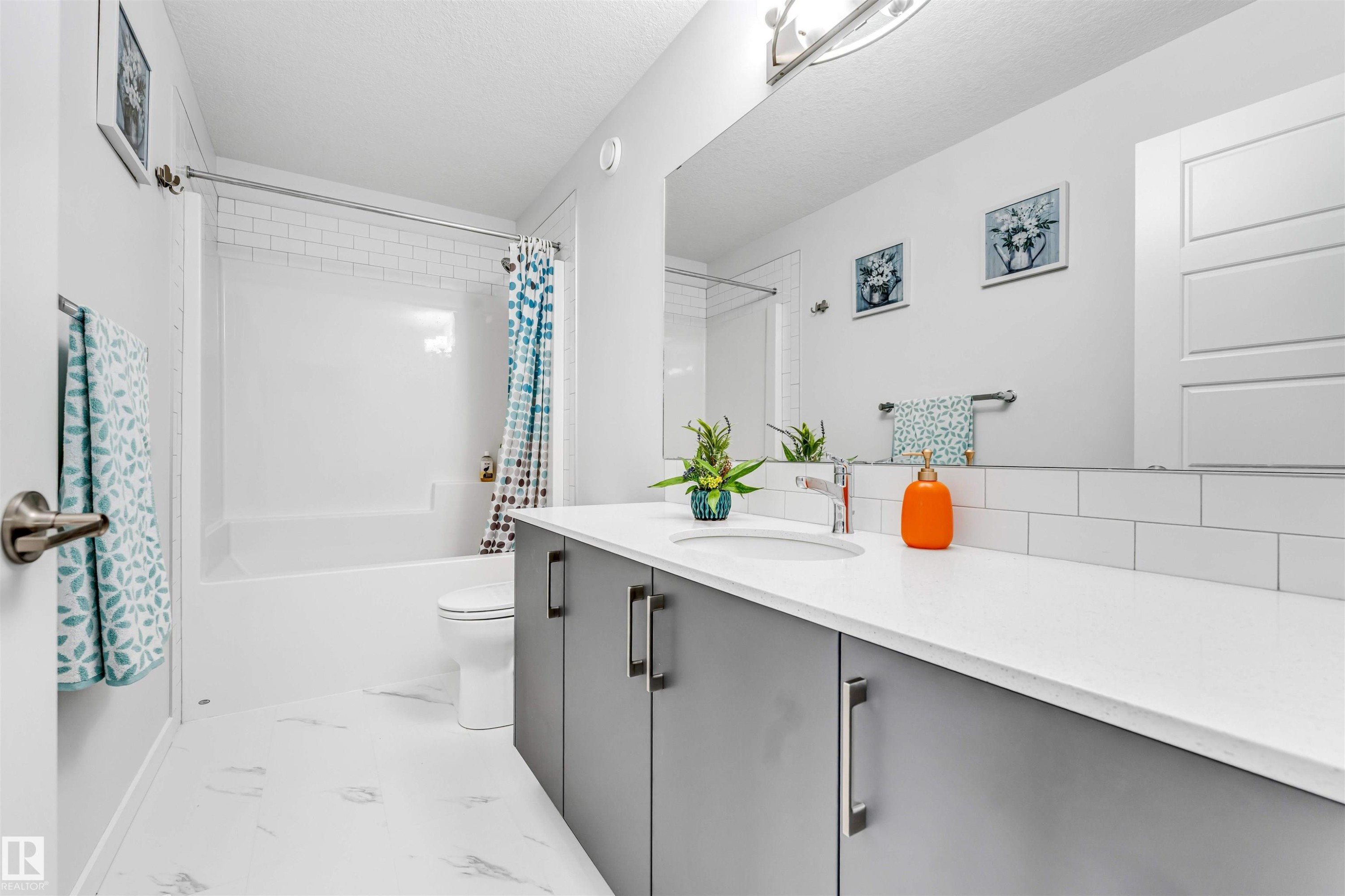 Bathroom featuring a white subway tile backsplash, a spacious vanity with gray cabinetry, and a large wall-mounted mirror - 425 41 Street, Edmonton, AB - Indoor Photo Showing Bathroom