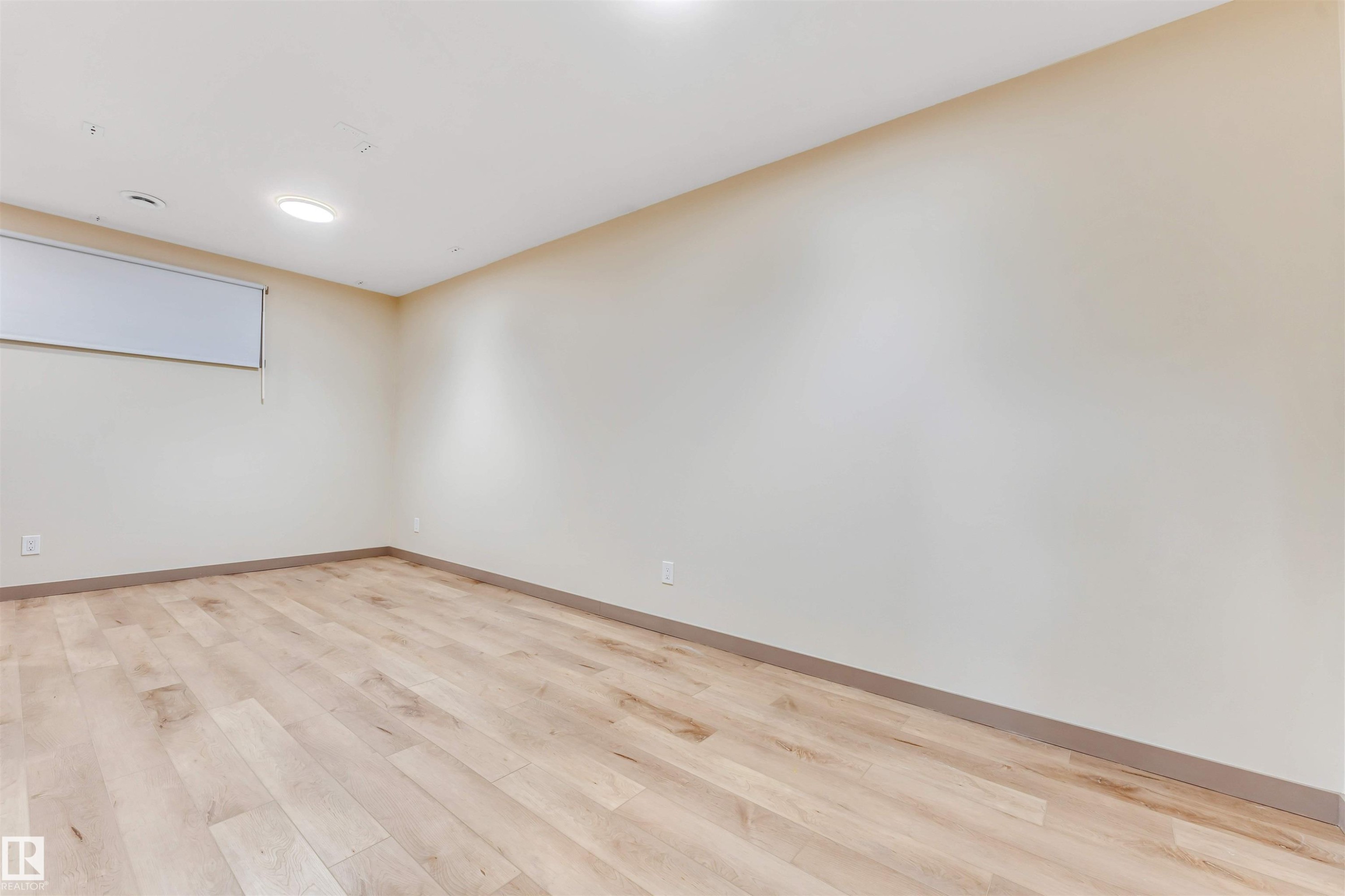 Bright, neutral-toned room featuring wood-finish flooring, a window with a roller shade, recessed lighting, and light-colored walls - 425 41 Street, Edmonton, AB - Indoor Photo Showing Other Room