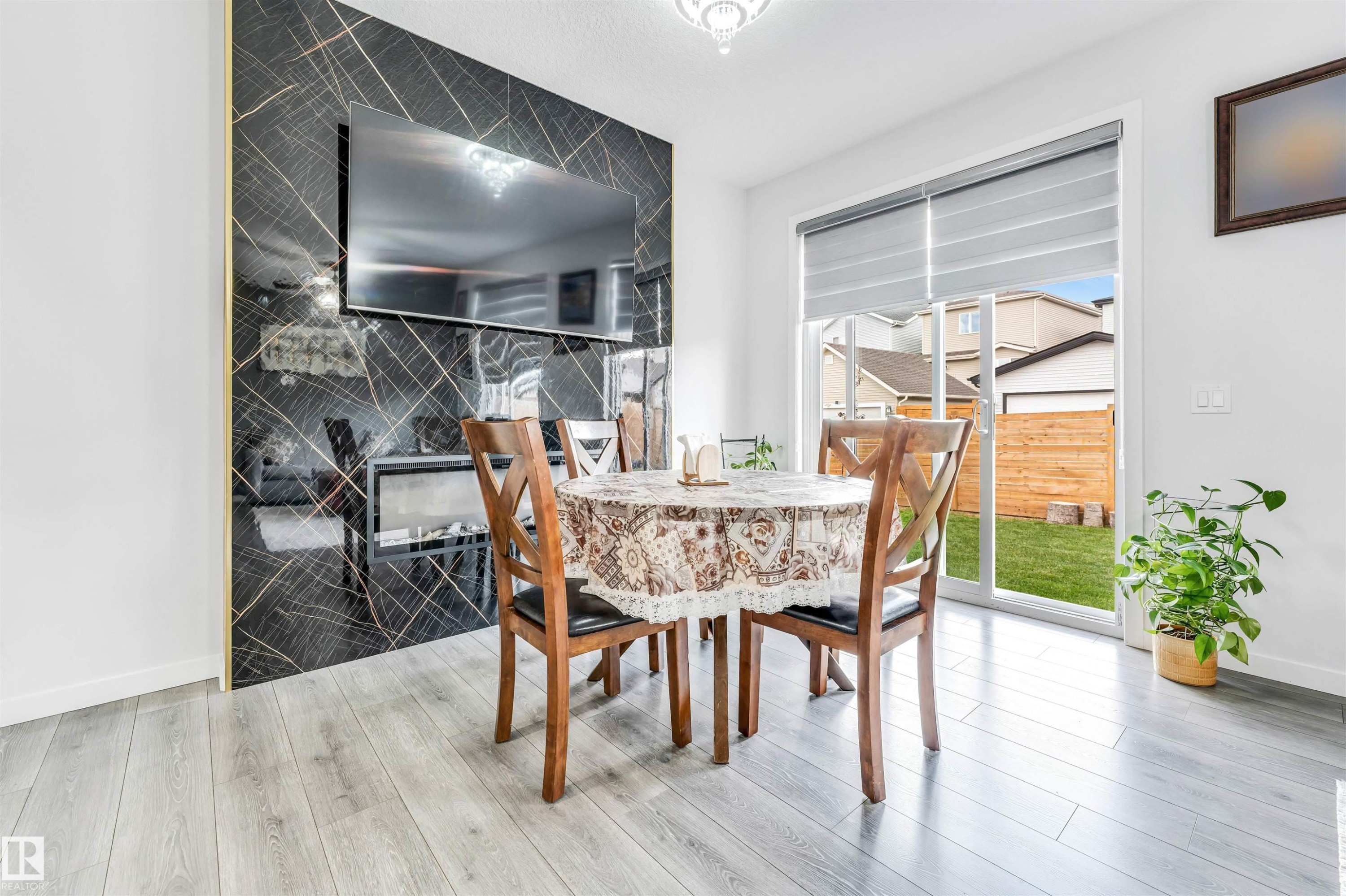 Modern accent wall featuring a wall-mounted media display, integrated fireplace, and striking black and gold patterned paneling - 425 41 Street, Edmonton, AB - Indoor Photo Showing Dining Room