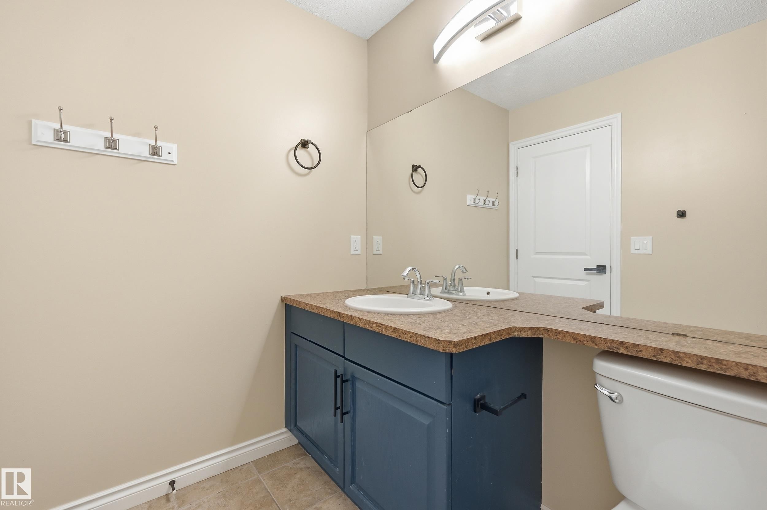 Bathroom featuring a dual vanity with a dark blue cabinet, light speckled countertop, and two integrated sinks - 1 Southfork Close, Leduc, AB - Indoor Photo Showing Bathroom