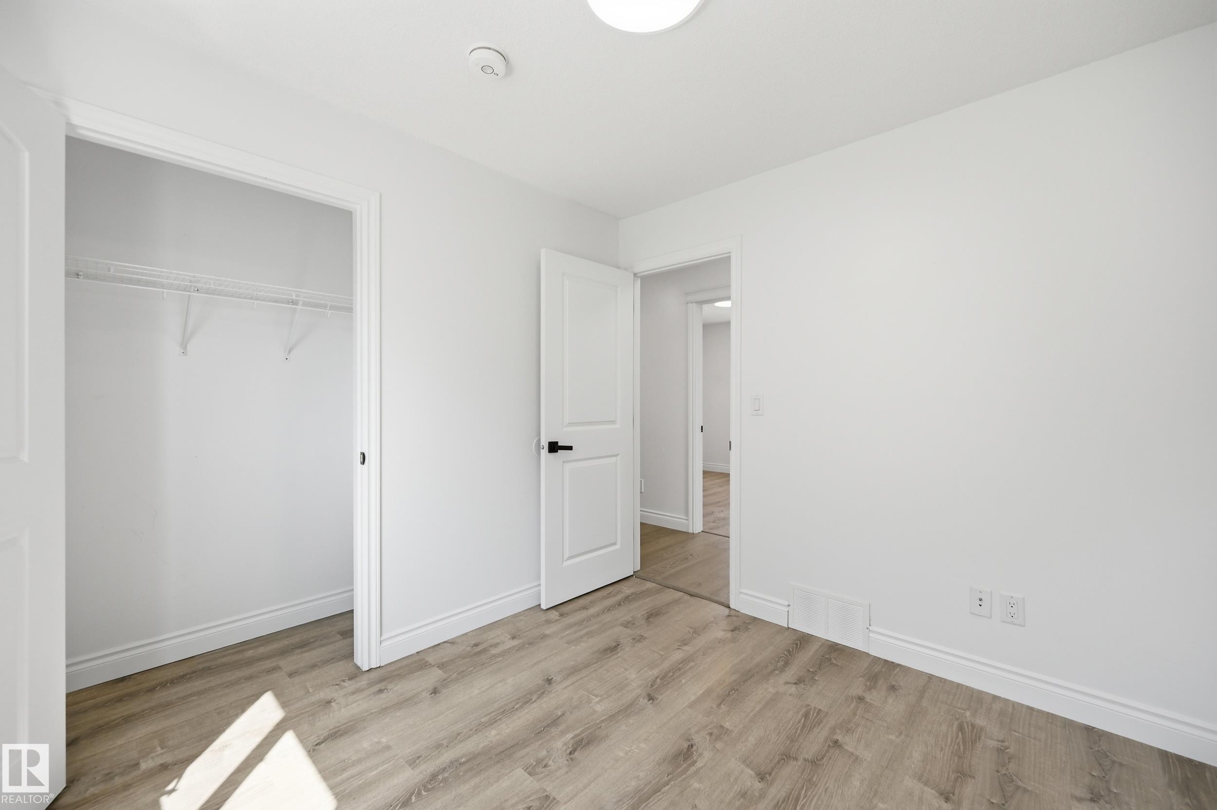Bright interior room featuring wood-finish flooring, white walls, and a white ceiling with a flush-mount light fixture - 1 Southfork Close, Leduc, AB - Indoor Photo Showing Other Room