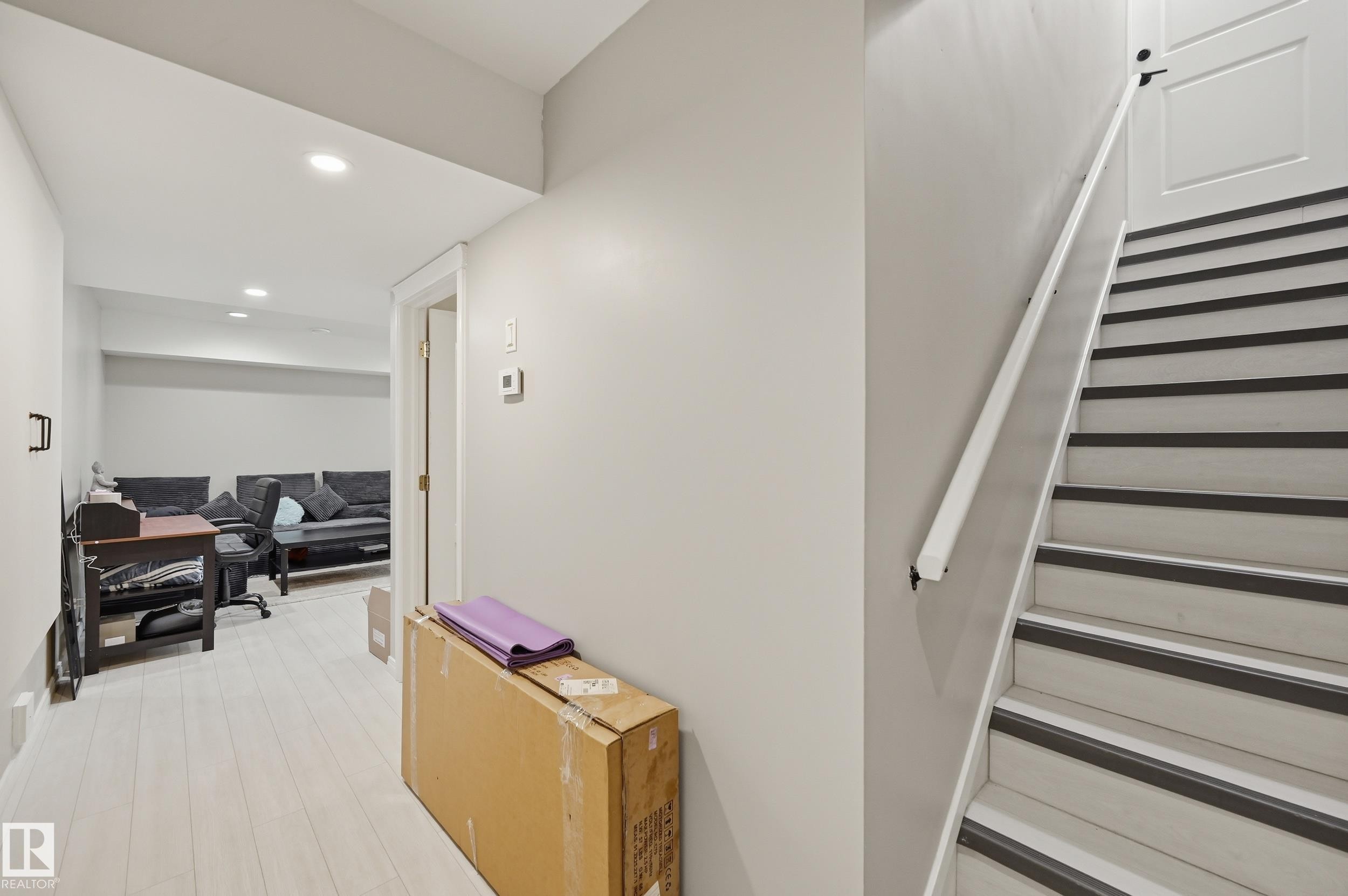 Staircase with light wood-finish treads and dark anti-slip strips, featuring a white handrail - 1 Southfork Close, Leduc, AB - Indoor Photo Showing Other Room