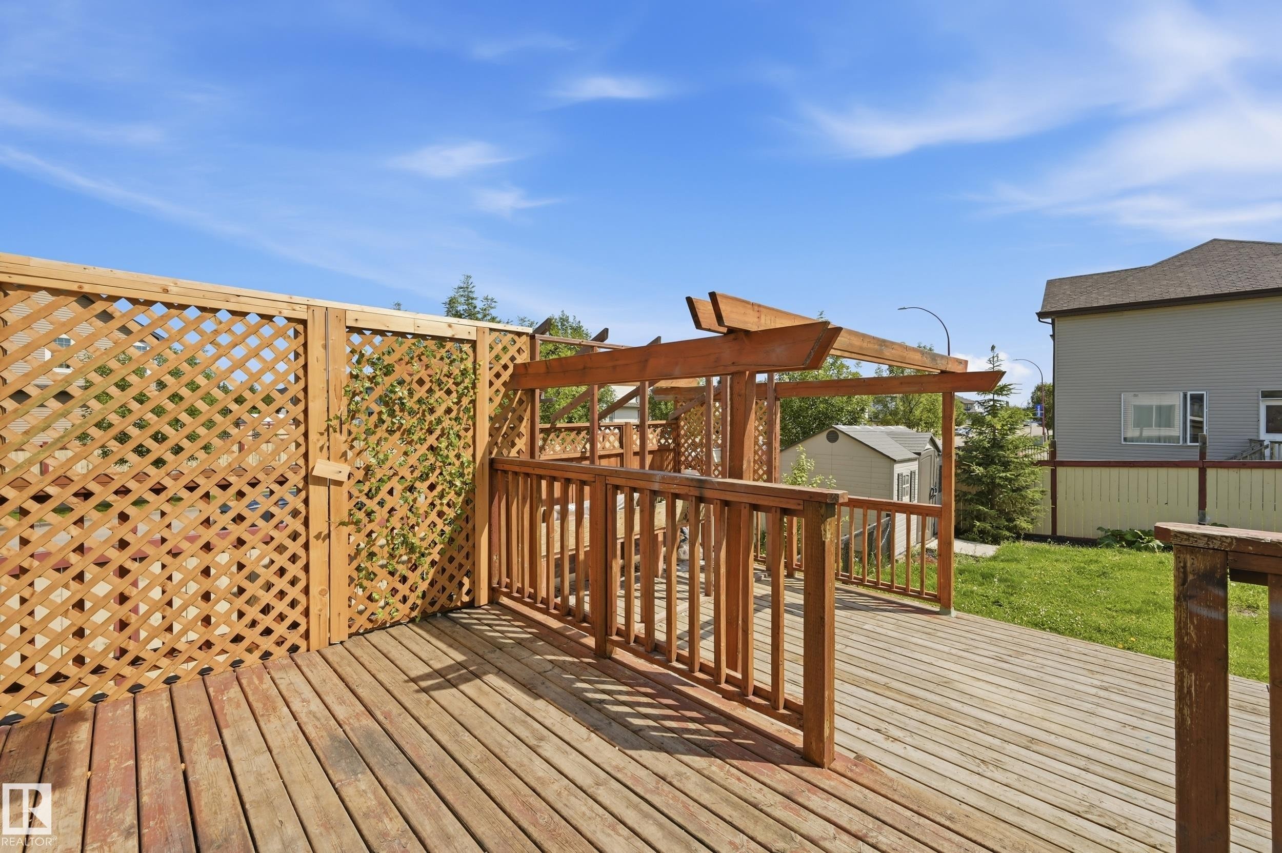 Expansive wood deck with a built-in pergola structure, featuring durable wood-plank flooring and natural wood lattice privacy fencing - 1 Southfork Close, Leduc, AB - Outdoor With Deck Patio Veranda