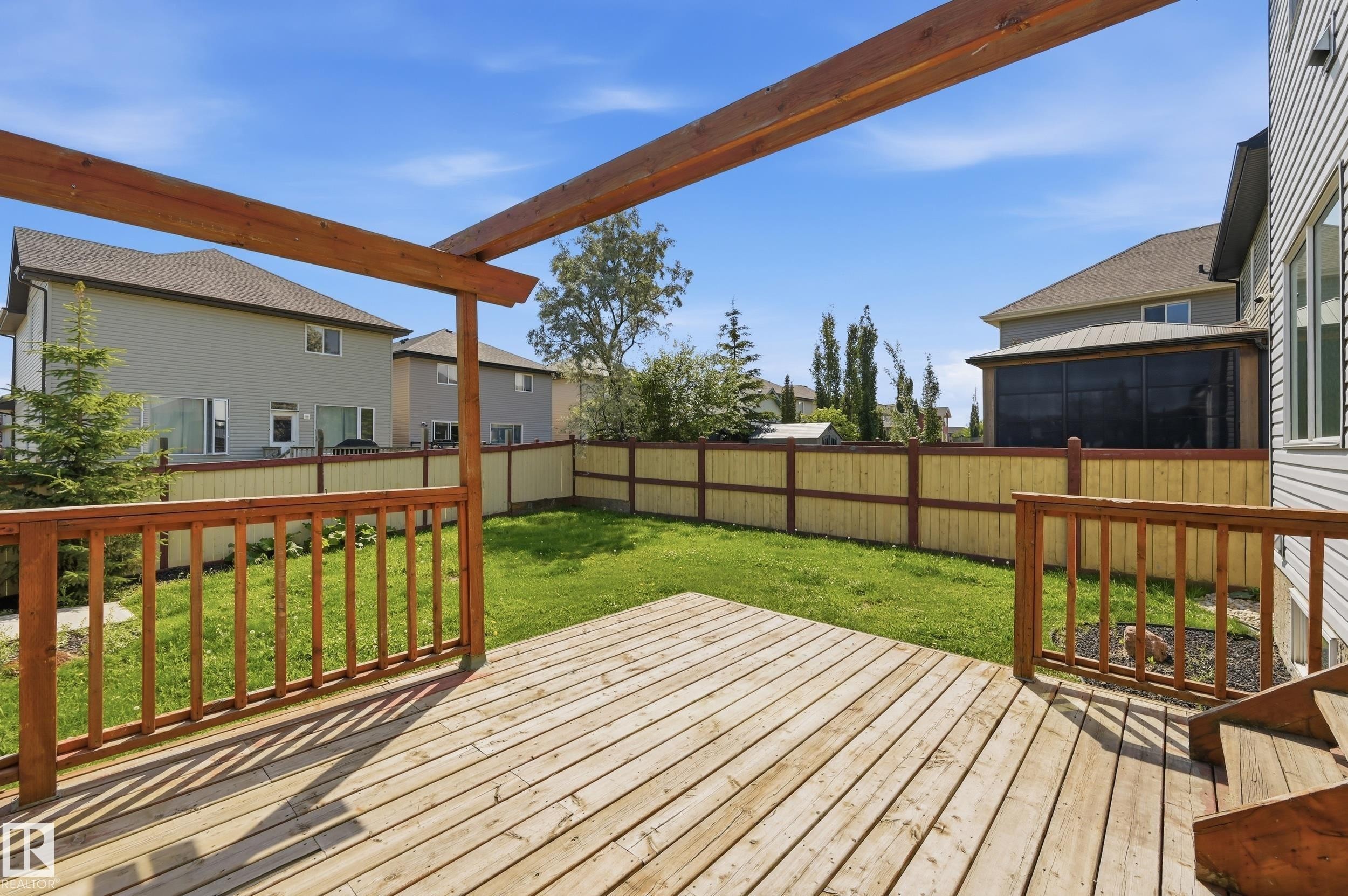 Expansive wood deck with a pergola frame, overlooking a private fenced yard with a manicured lawn - 1 Southfork Close, Leduc, AB - Outdoor With Deck Patio Veranda
