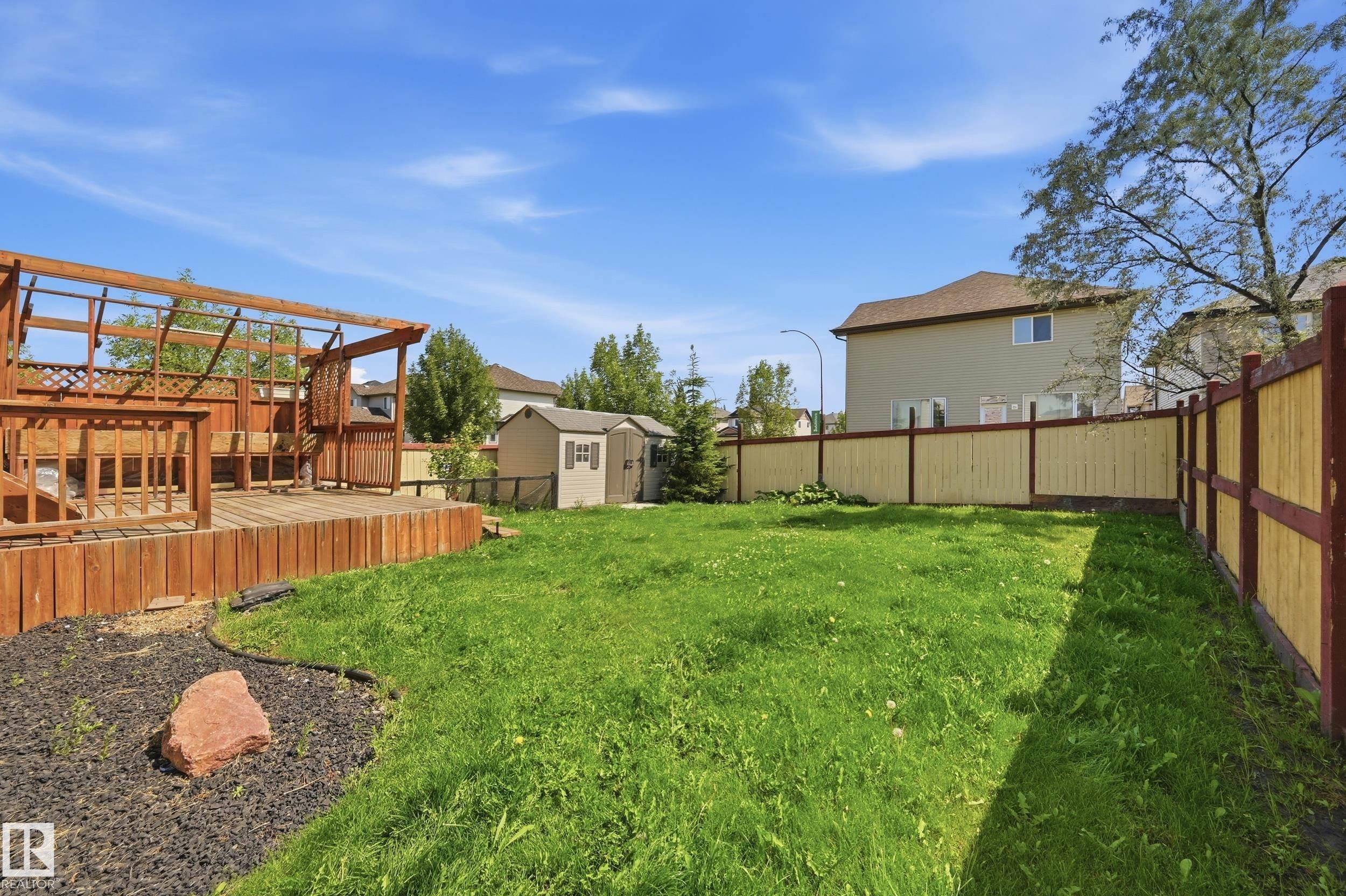 Lawn area with a multi-level wood deck, wood pergola, and a storage shed - 1 Southfork Close, Leduc, AB - Outdoor With Deck Patio Veranda With Backyard