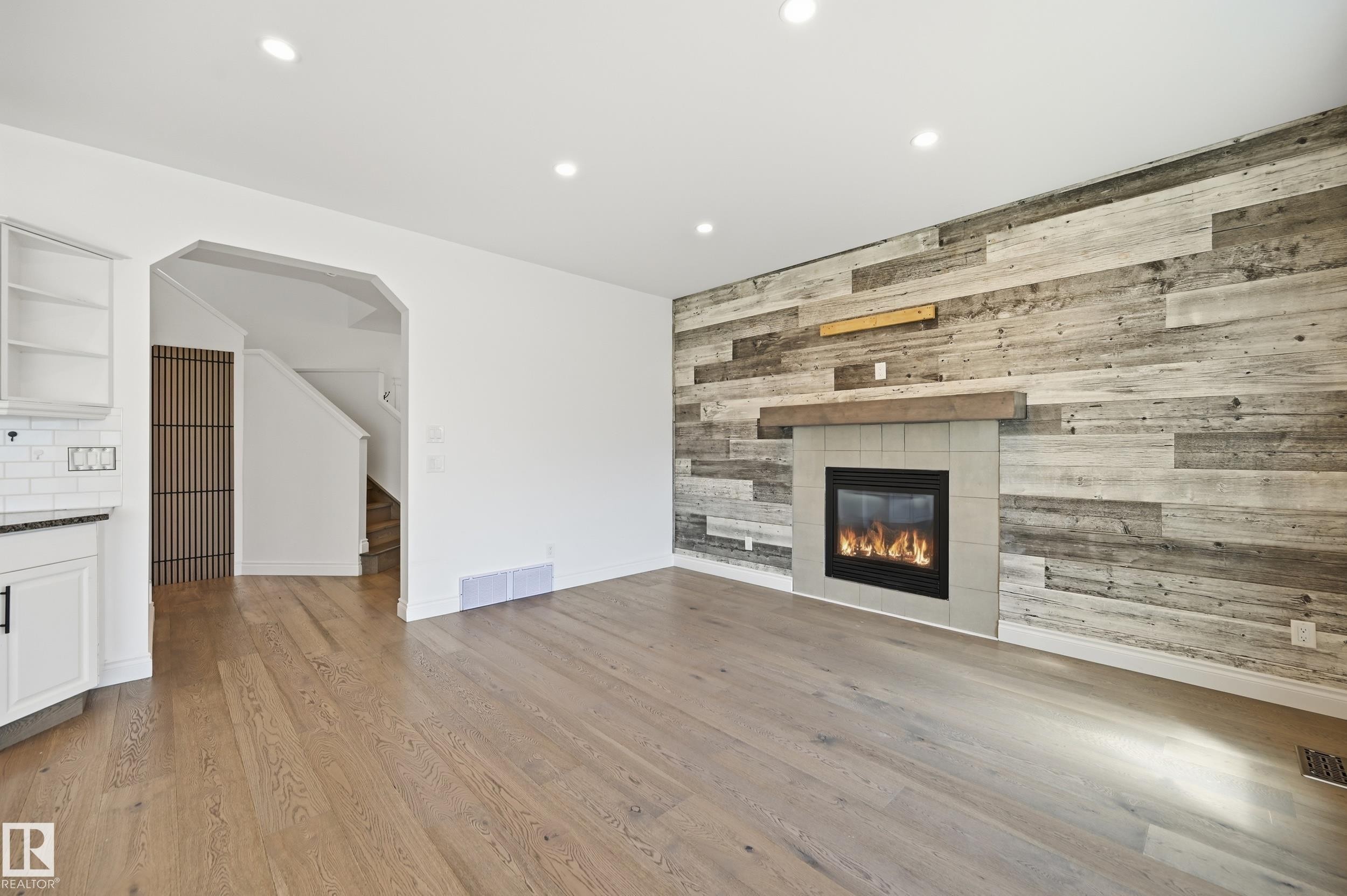 Living area featuring a reclaimed wood-style accent wall with a built-in fireplace and wood mantel - 1 Southfork Close, Leduc, AB - Indoor Photo Showing Living Room With Fireplace