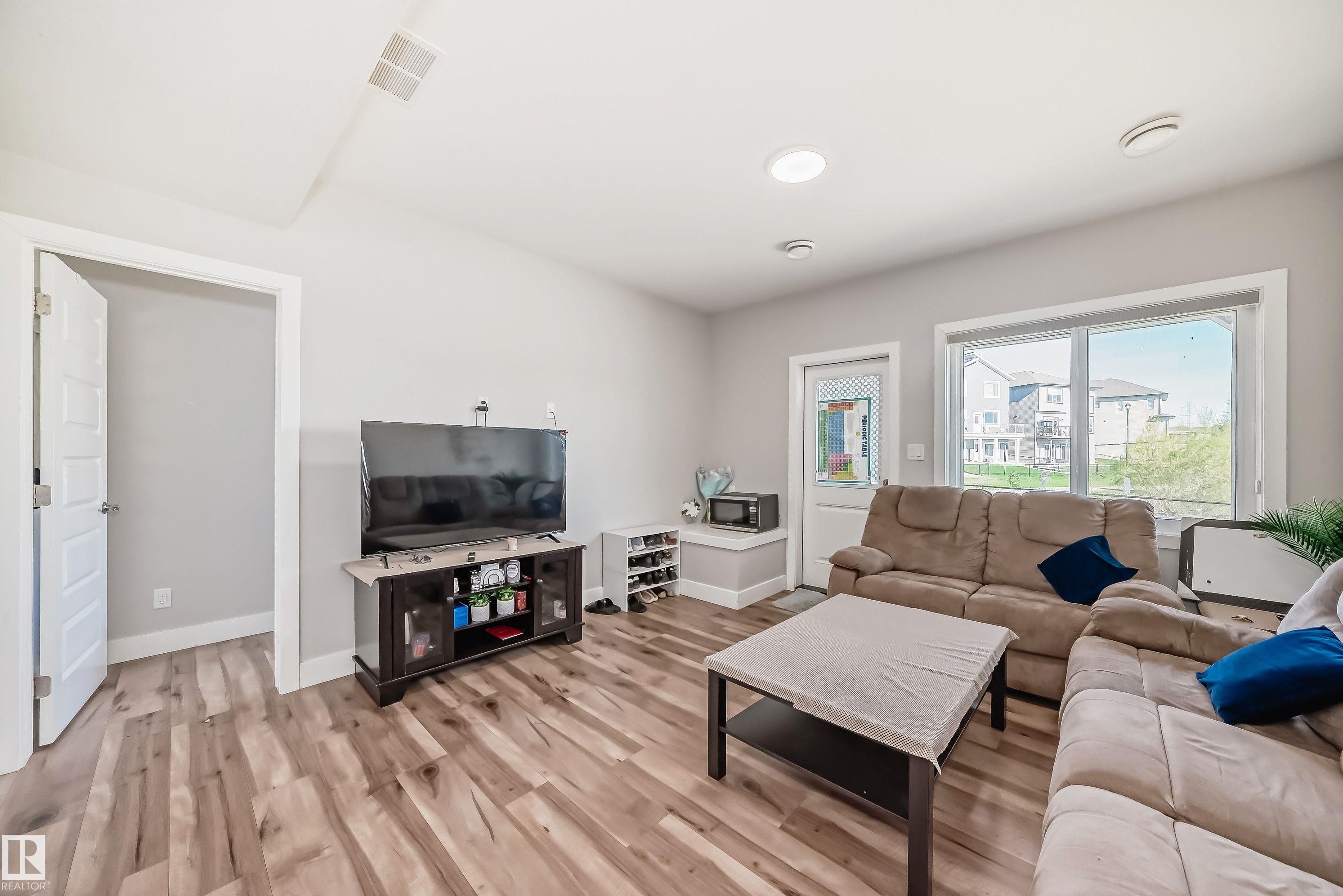 Spacious living area featuring wood-finish flooring and light gray walls - 2464 15 Avenue Nw, Edmonton, AB - Indoor Photo Showing Living Room