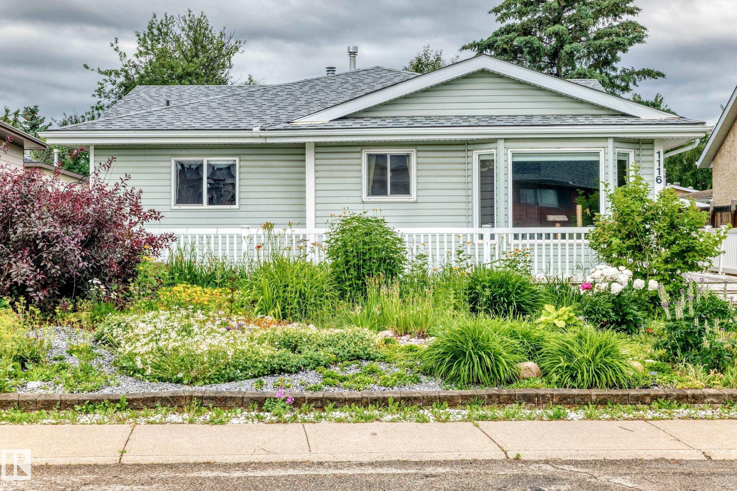 Front exterior featuring light-colored siding, a gabled roofline, and a white picket fence - 1116 39 Street Nw, Edmonton, AB - Outdoor