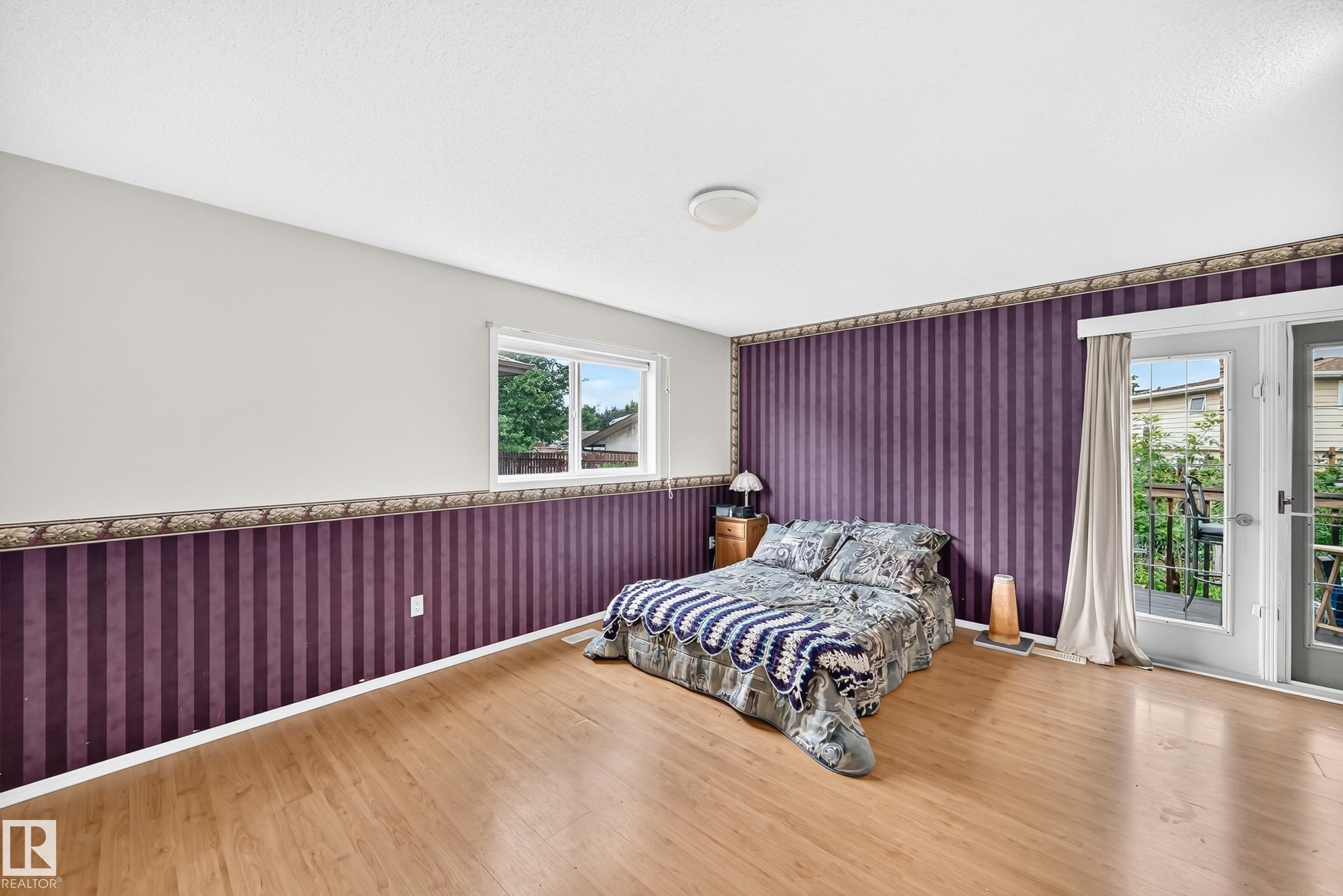 Room featuring wood-finish flooring, a double window, and French doors opening to an exterior deck - 1116 39 Street Nw, Edmonton, AB - Indoor Photo Showing Bedroom