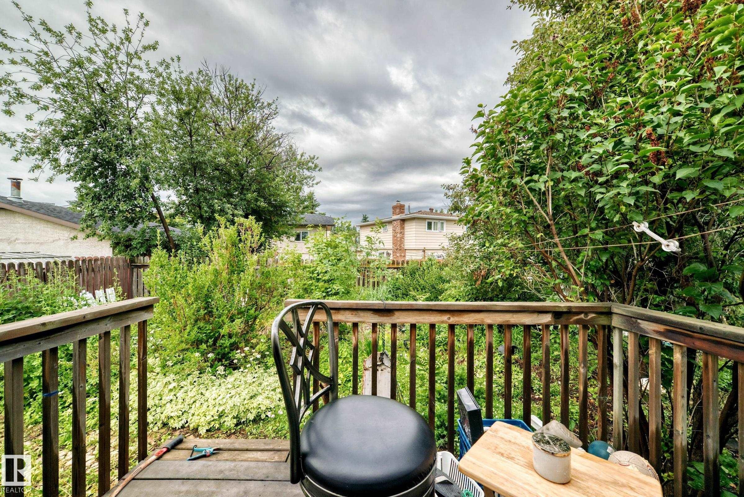 Wood deck featuring wood railing and lush surrounding foliage - 1116 39 Street Nw, Edmonton, AB - Outdoor
