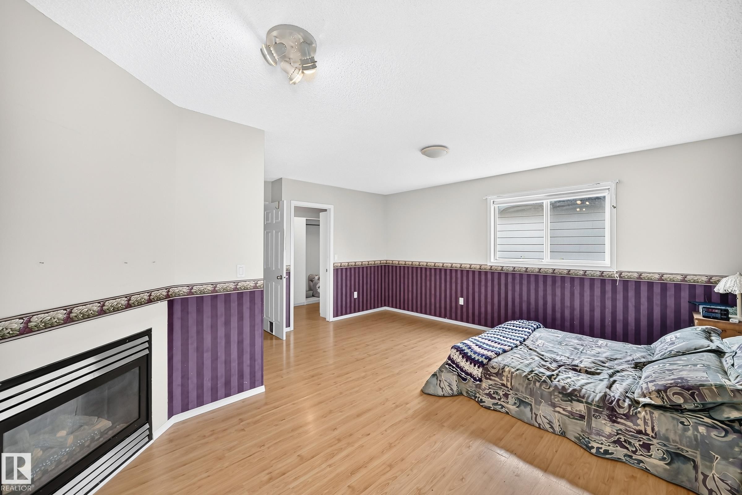 Room featuring wood-finish flooring, a built-in fireplace, and a window with white trim - 1116 39 Street Nw, Edmonton, AB - Indoor Photo Showing Other Room