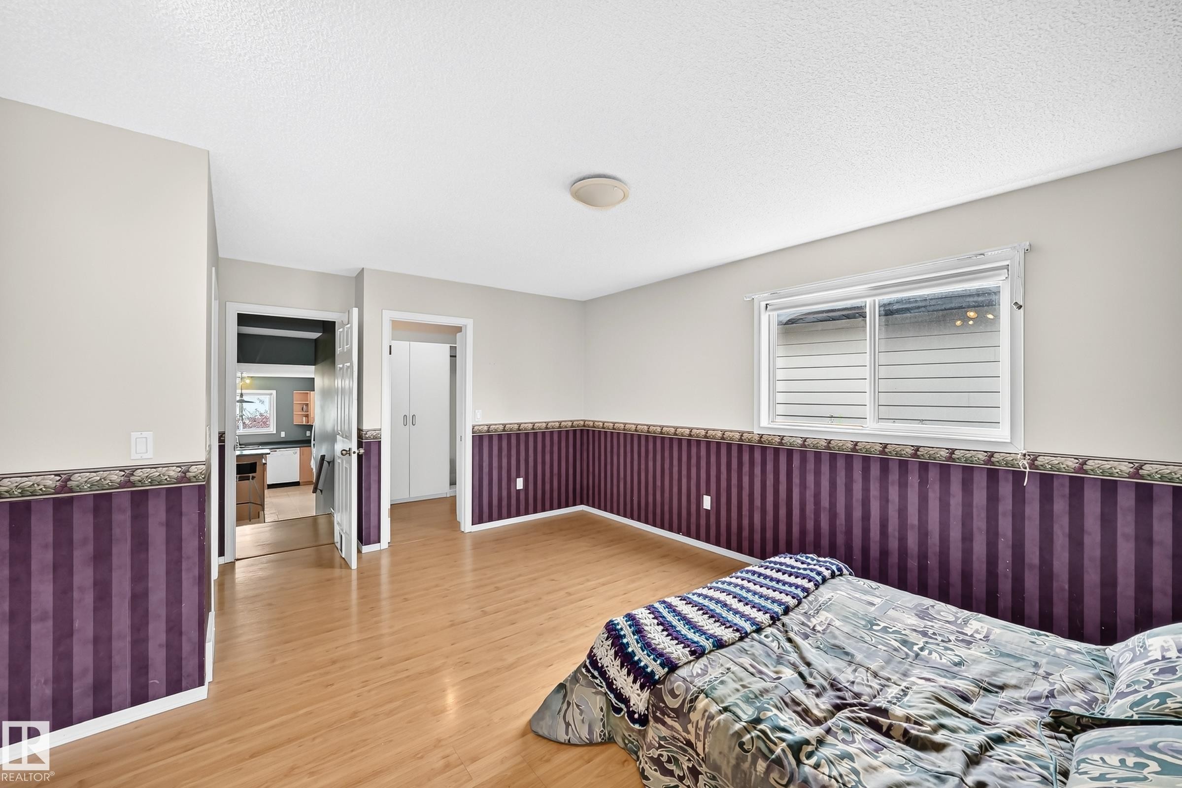 Spacious room featuring wood-finish flooring, a window offering natural light, and a built-in closet with bi-fold doors - 1116 39 Street Nw, Edmonton, AB - Indoor Photo Showing Bedroom