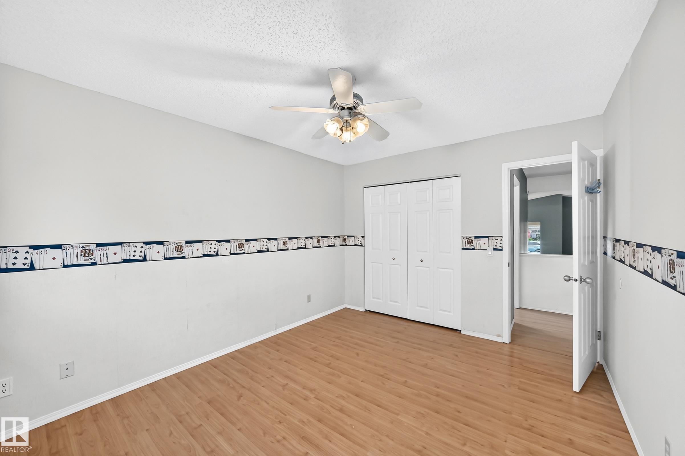 Room featuring wood-finish flooring, a ceiling fan with integrated lighting, and a bi-fold closet door - 1116 39 Street Nw, Edmonton, AB - Indoor Photo Showing Other Room