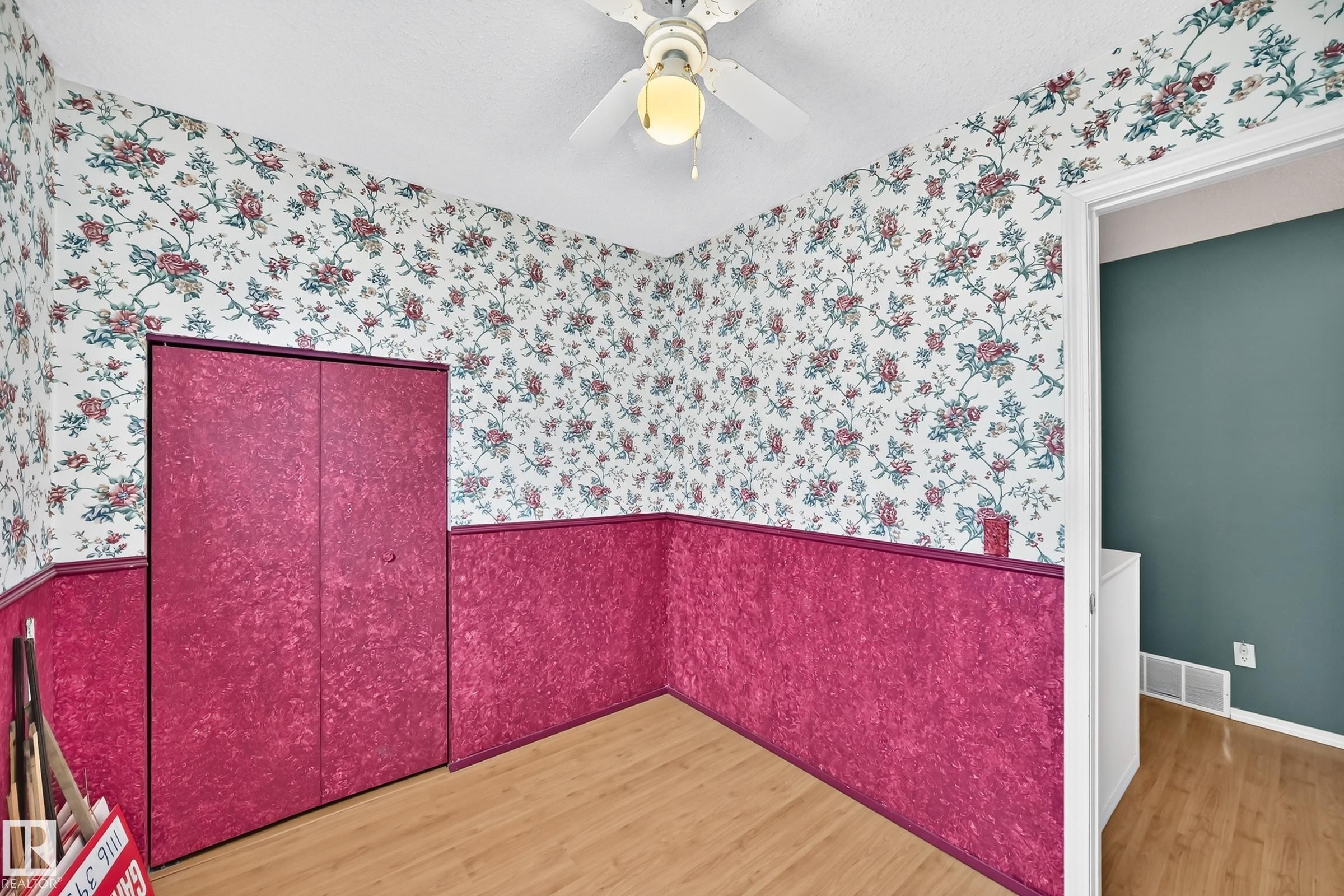 Neutral-toned wood-finish flooring complements the room's floral wallpaper and textured lower wall paneling - 1116 39 Street Nw, Edmonton, AB - Indoor
