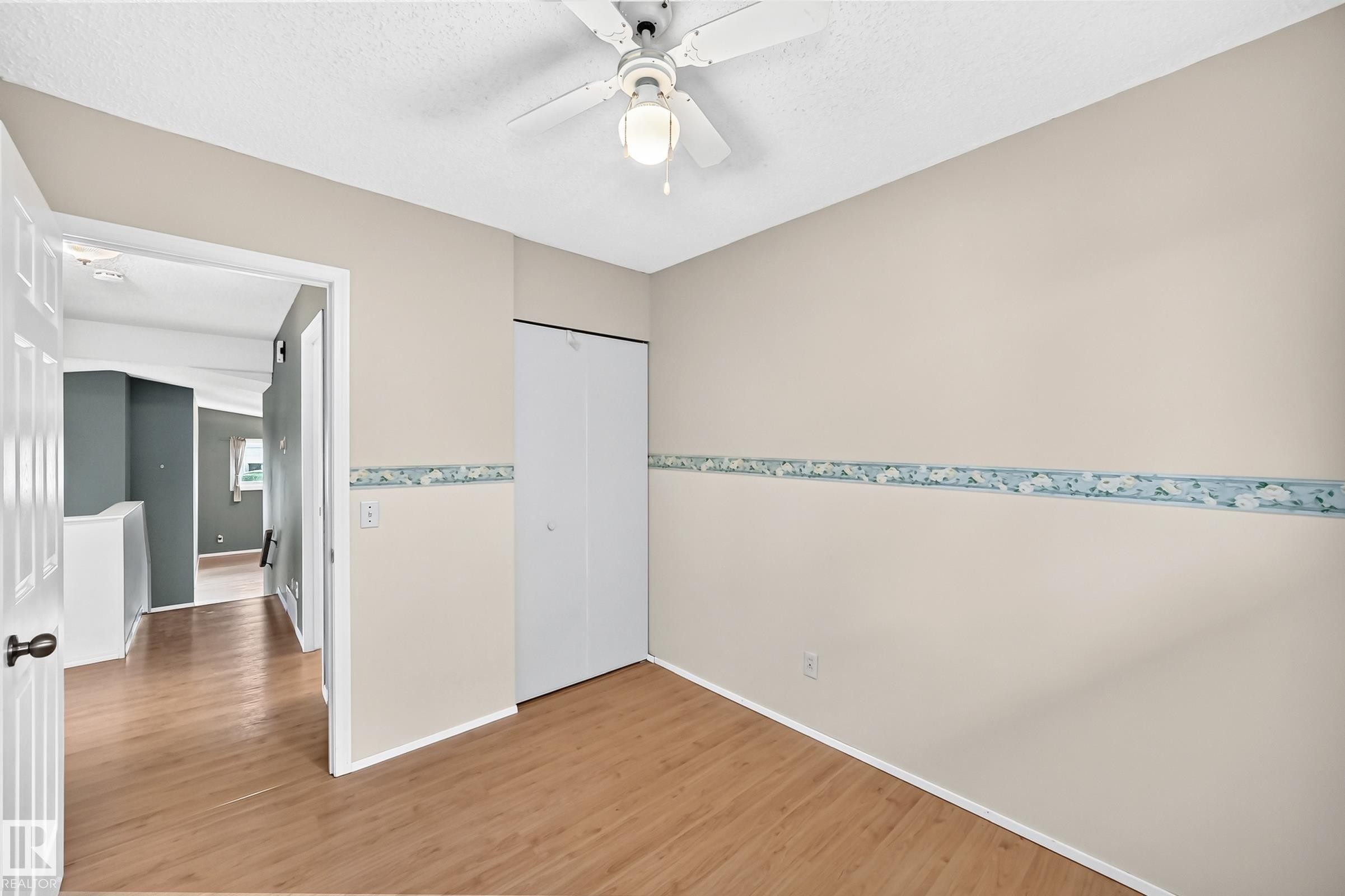Interior room featuring wood-finish flooring, light neutral wall paint, and a ceiling fan with integrated lighting - 1116 39 Street Nw, Edmonton, AB - Indoor Photo Showing Other Room