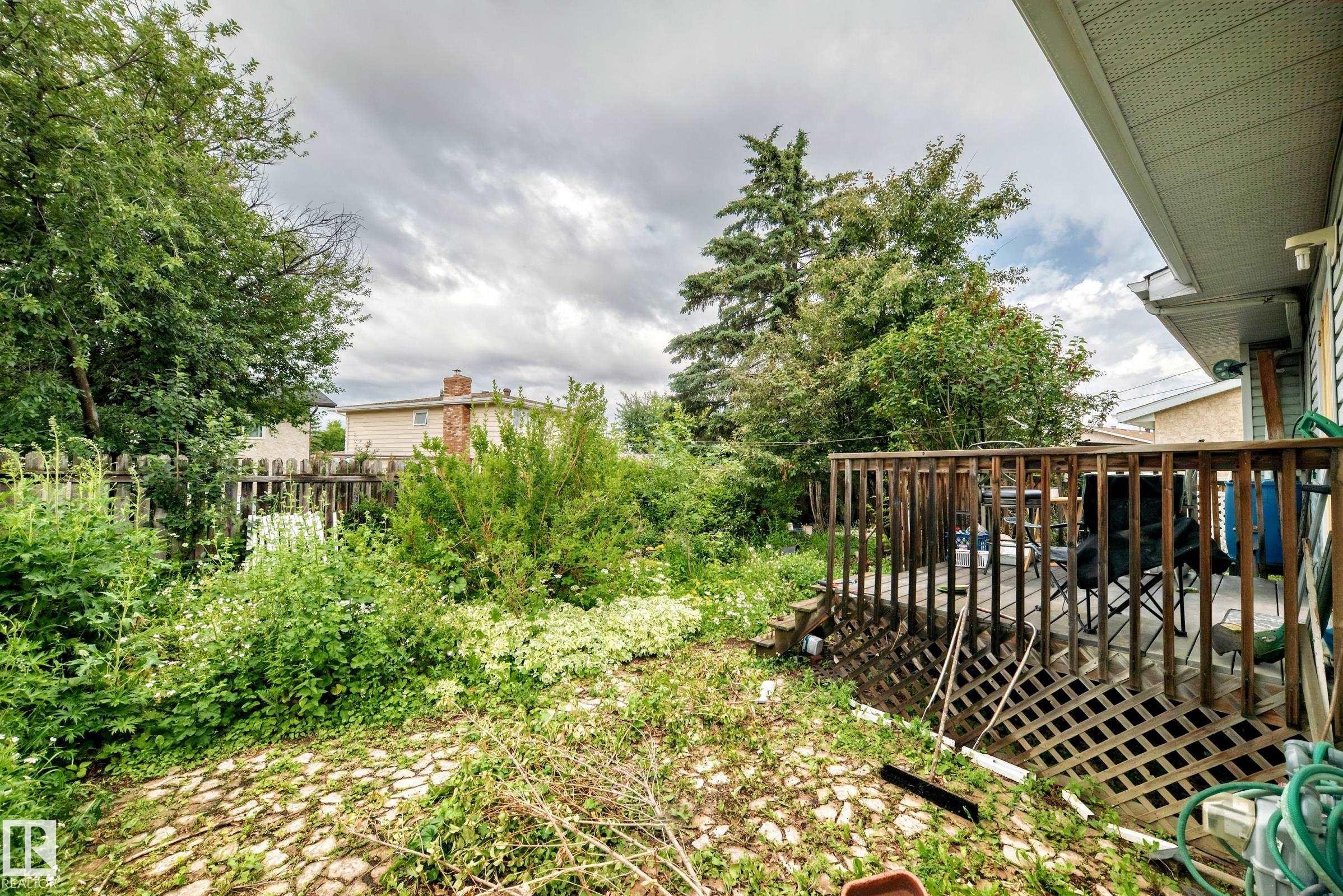 Spacious backyard featuring a wooden deck with railing, lattice skirting, and a paver stone patio area - 1116 39 Street Nw, Edmonton, AB - Outdoor