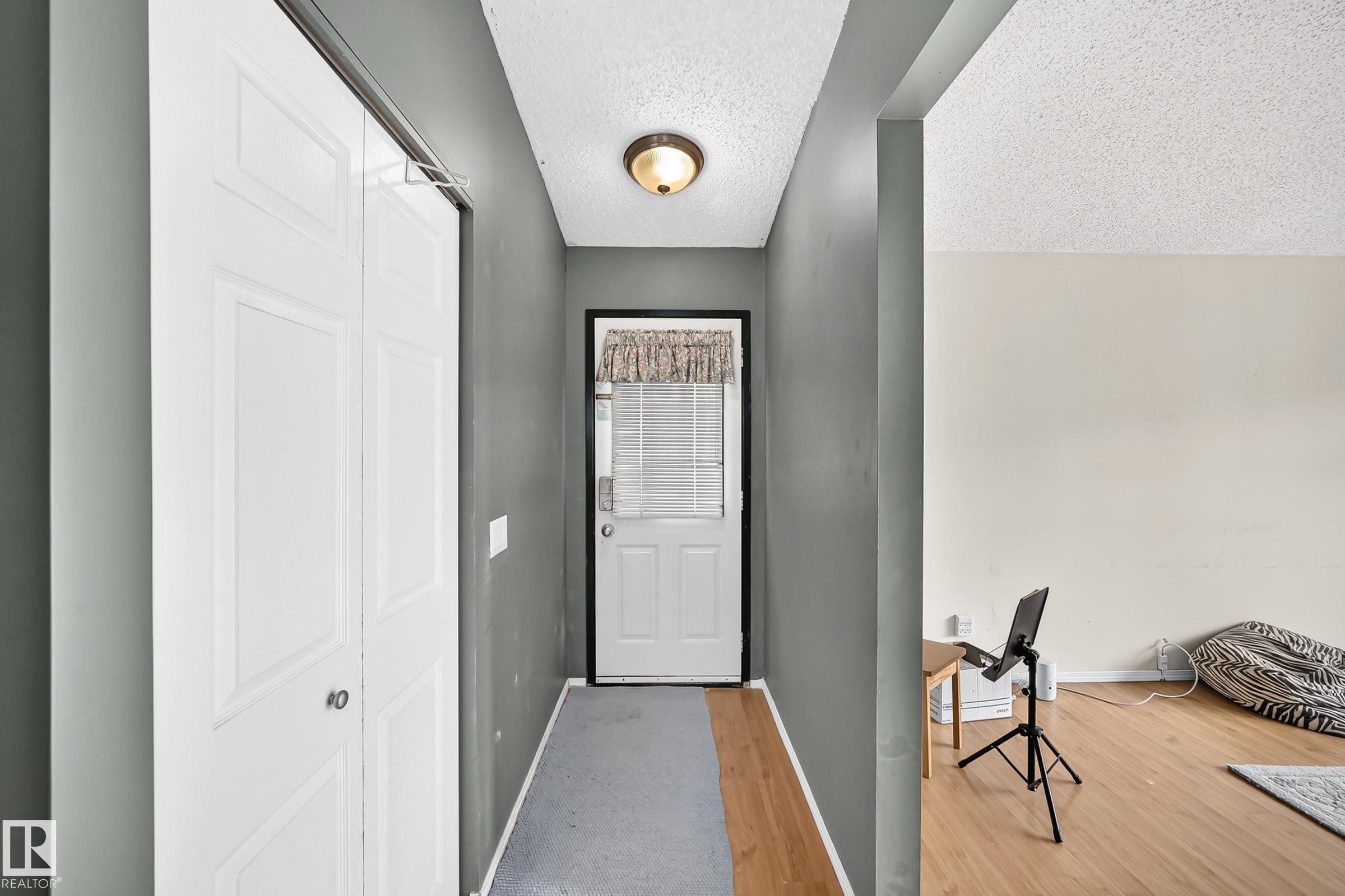 Entryway featuring a panel door, ceiling-mounted light fixture, and wood-finish flooring - 1116 39 Street Nw, Edmonton, AB - Indoor Photo Showing Other Room