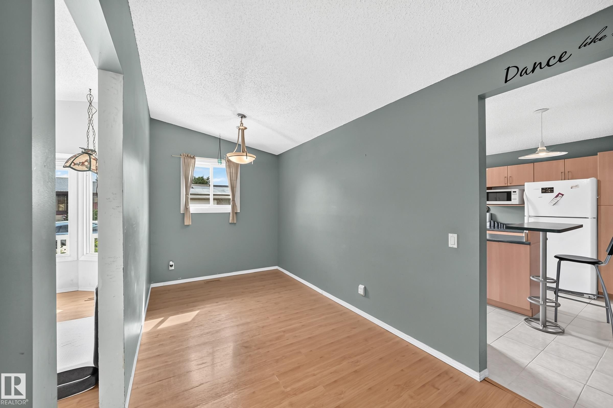 Open-concept living area featuring wood-finish flooring, a vaulted ceiling, and a prominent window - 1116 39 Street Nw, Edmonton, AB - Indoor