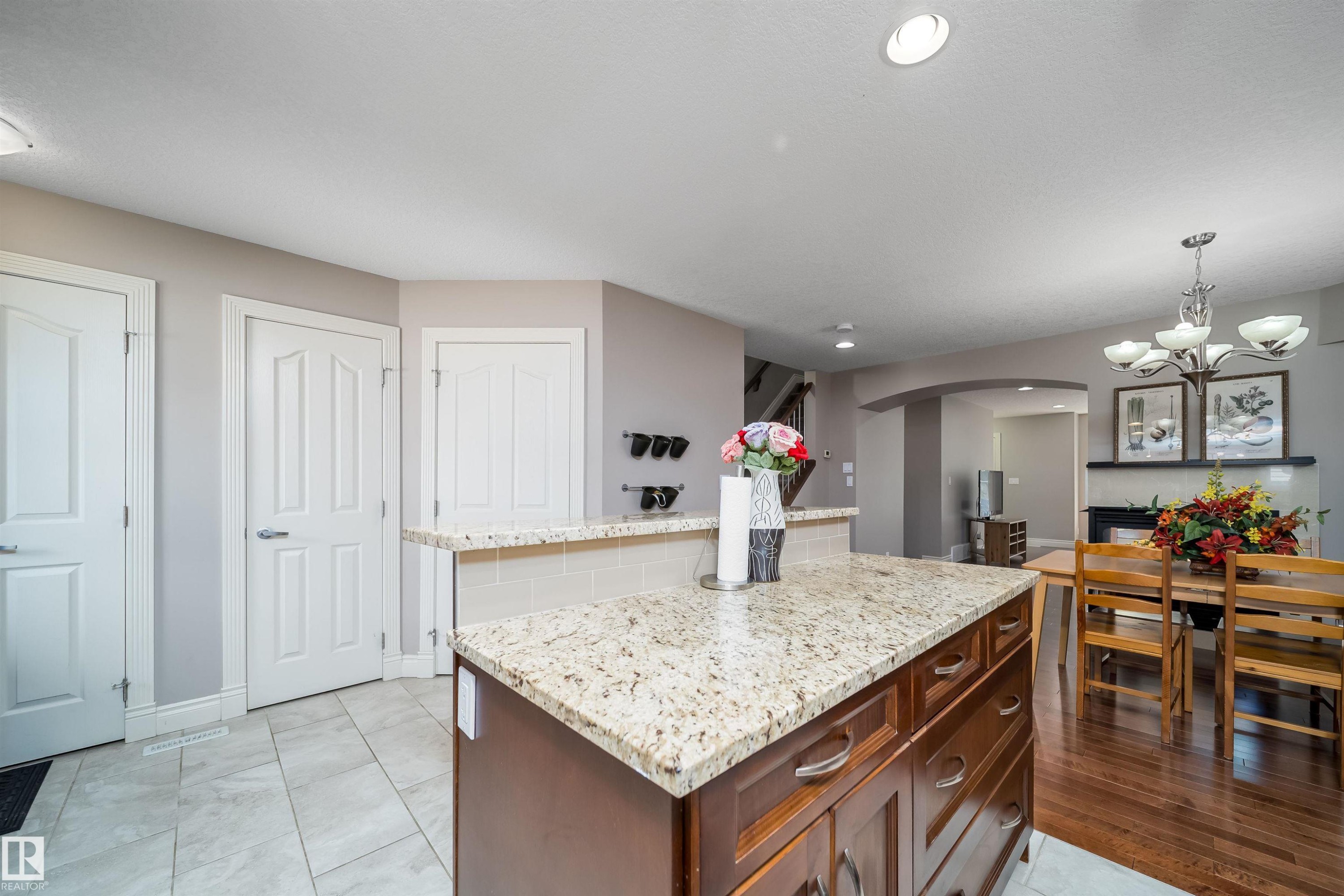 Kitchen island featuring a light granite countertop with a tile backsplash - 11342 79 Avenue, Edmonton, AB - Indoor