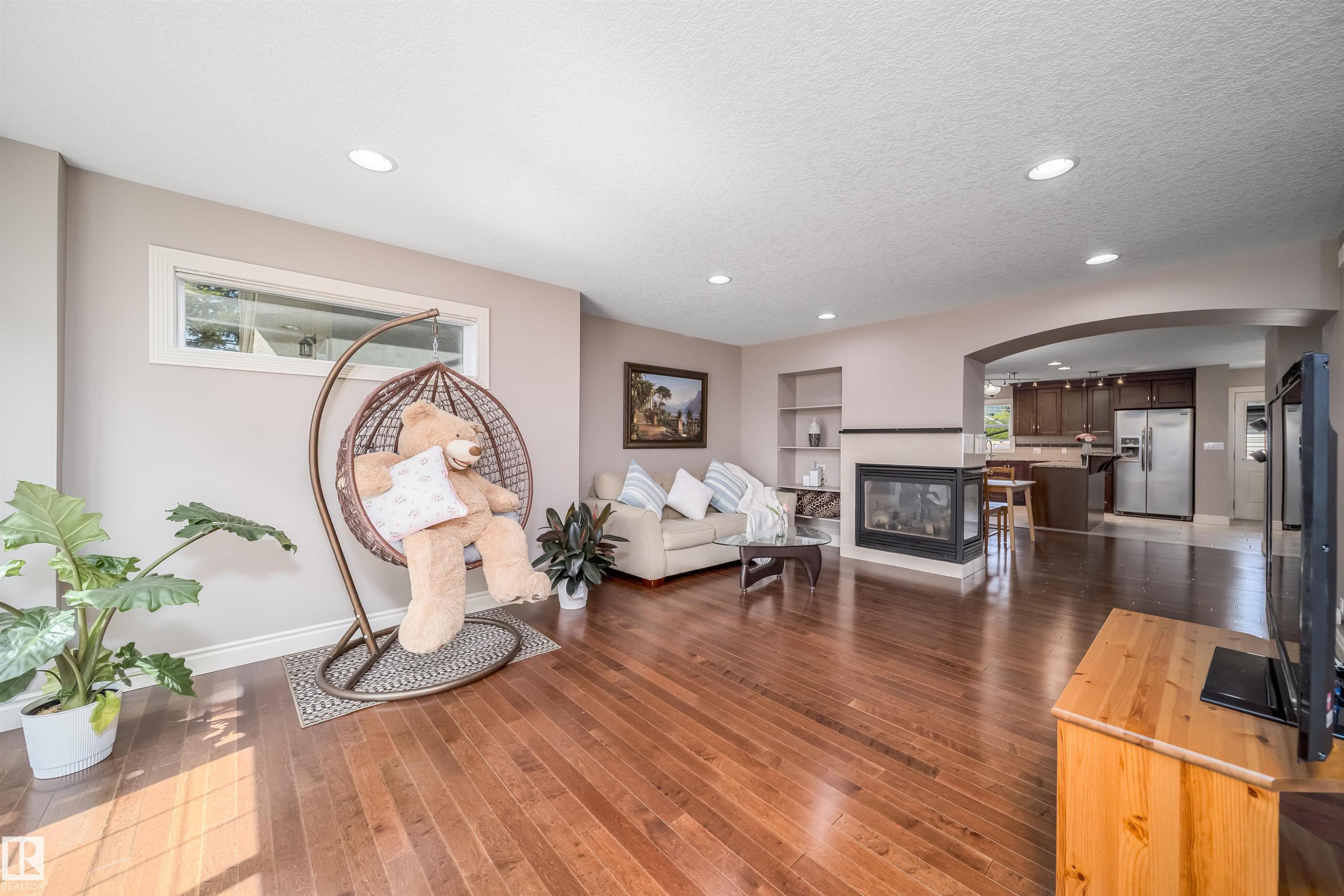 Spacious living area featuring wood-finish flooring, recessed lighting, and a horizontal window - 11342 79 Avenue, Edmonton, AB - Indoor With Fireplace