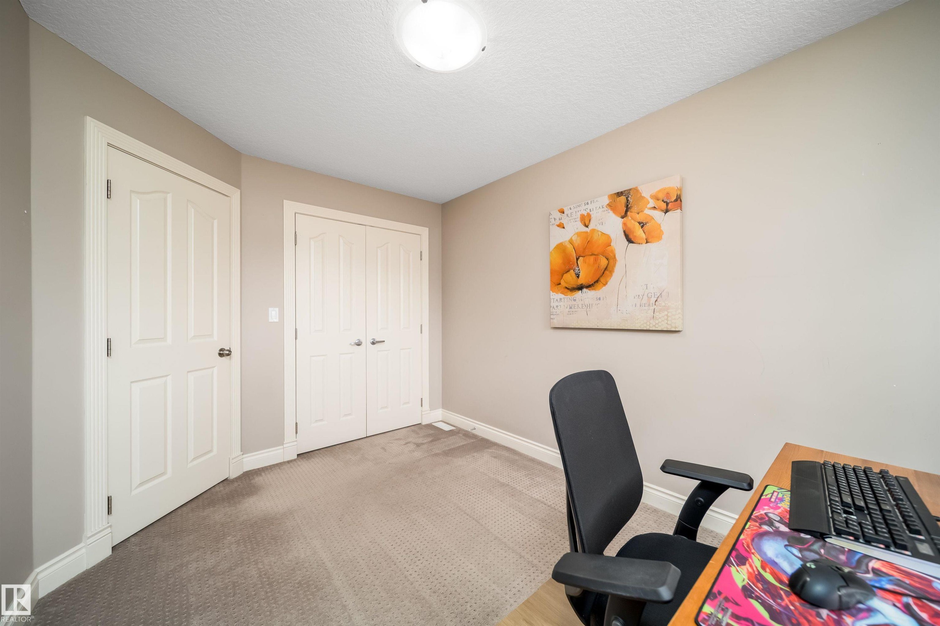 Neutral-toned room featuring a single panel door, a double bifold door, textured carpeting, and a flush mount ceiling light - 11342 79 Avenue, Edmonton, AB - Indoor Photo Showing Office