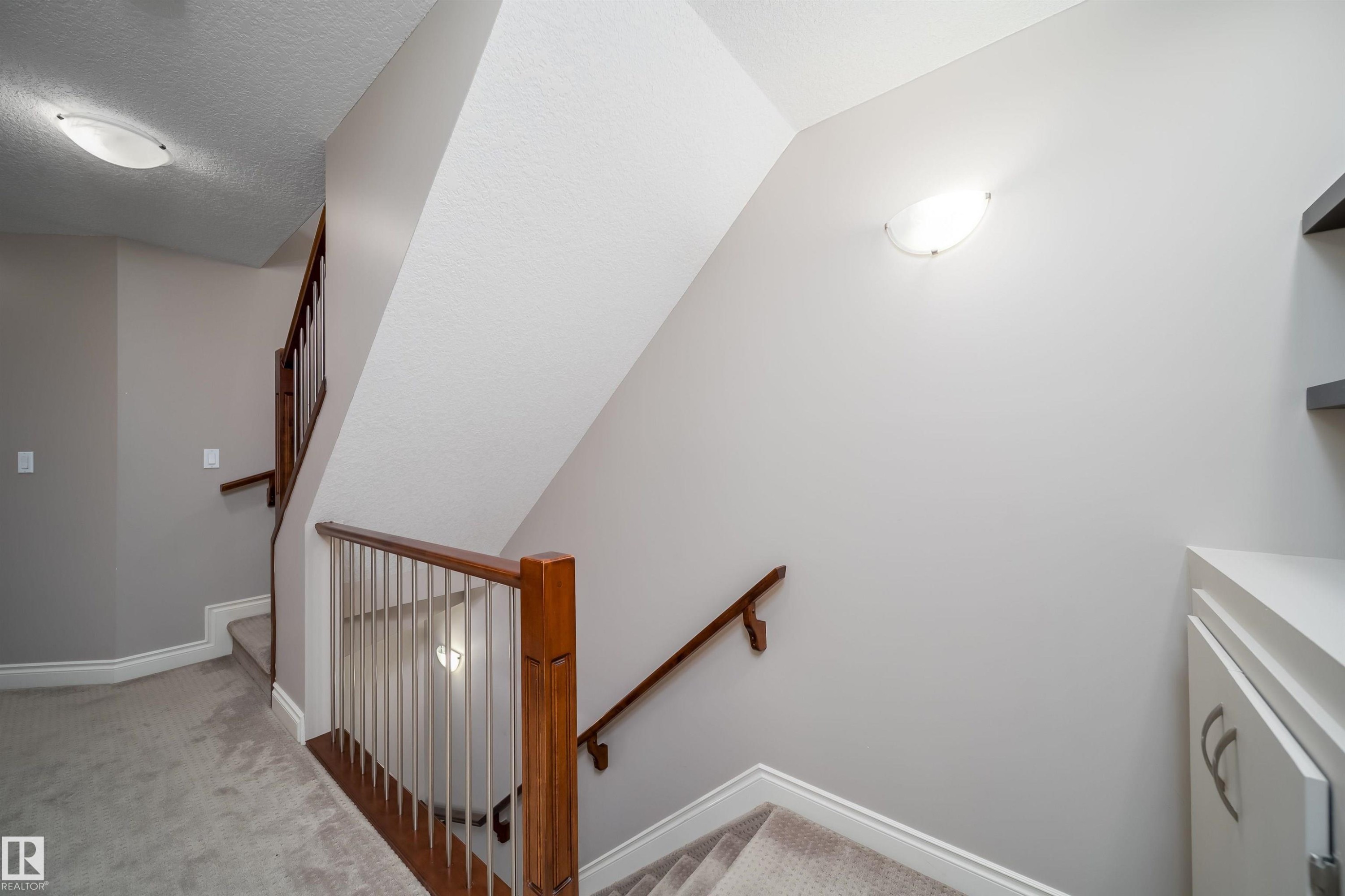 Carpeted staircase with wood handrails and white balusters - 11342 79 Avenue, Edmonton, AB - Indoor Photo Showing Other Room