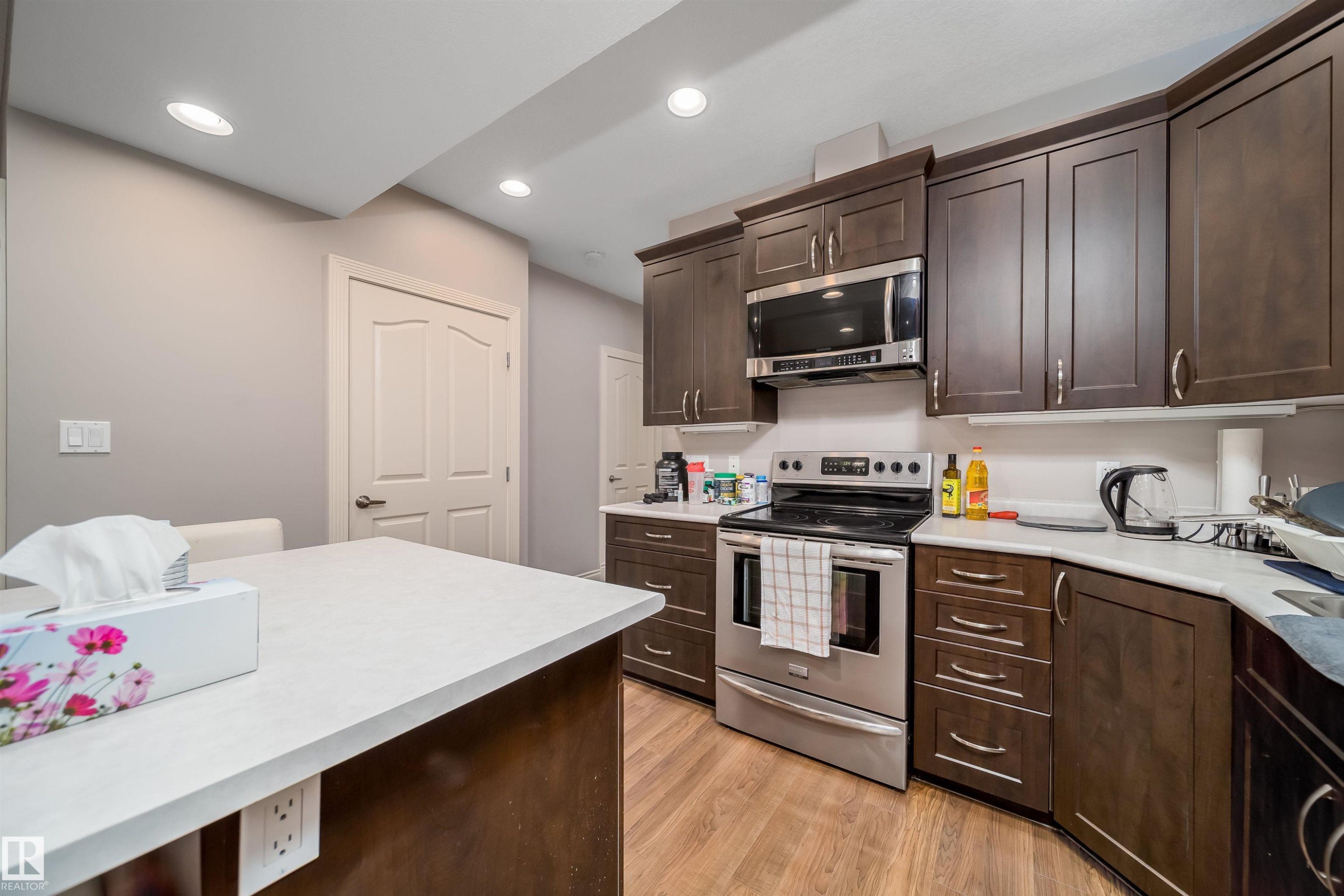 Kitchen featuring dark wood-finish cabinetry, stainless steel appliances, and wood-finish flooring - 11342 79 Avenue, Edmonton, AB - Indoor Photo Showing Kitchen