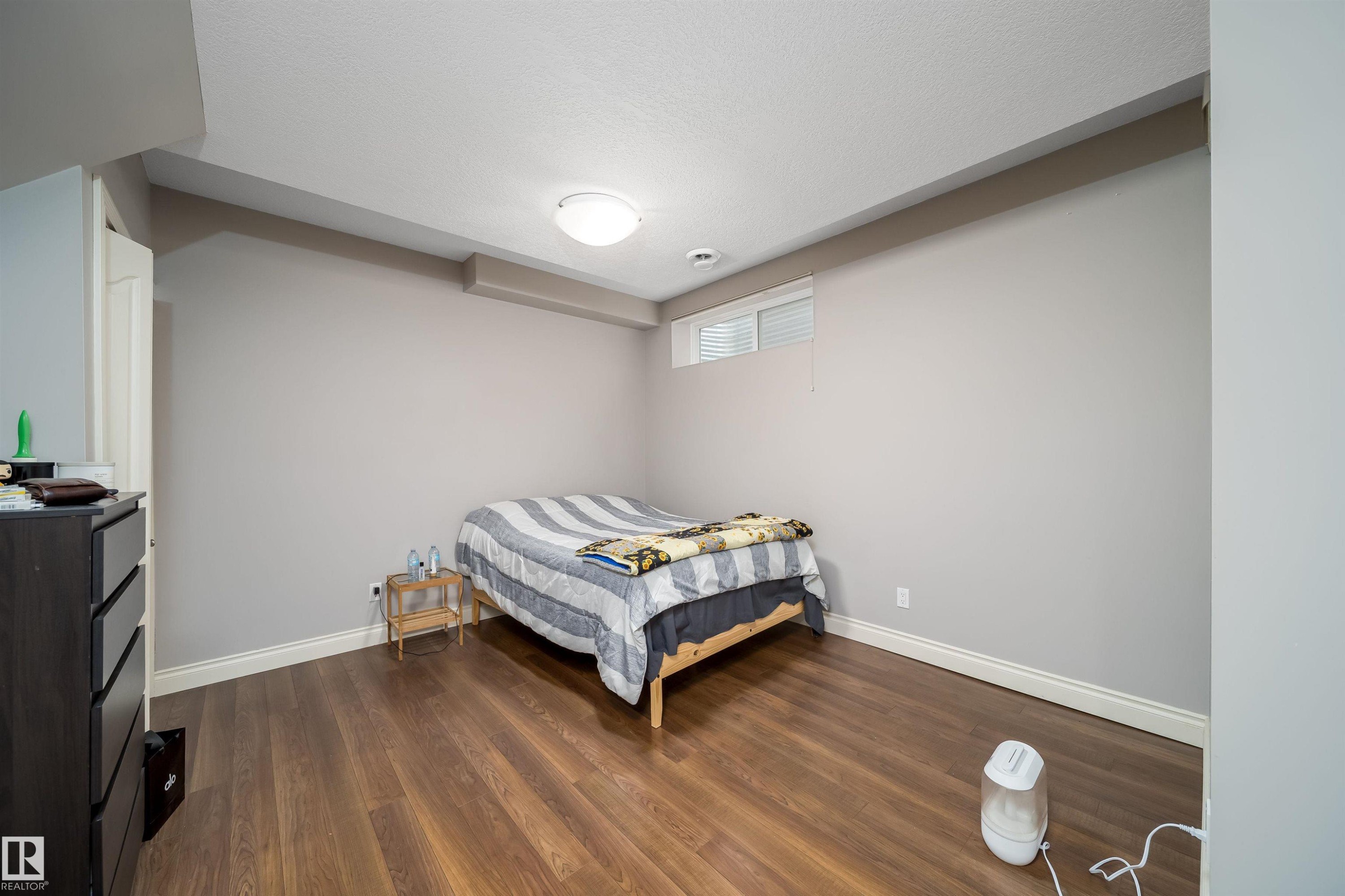 Spacious room with wood-finish flooring, light gray walls, and white trim - 11342 79 Avenue, Edmonton, AB - Indoor Photo Showing Bedroom