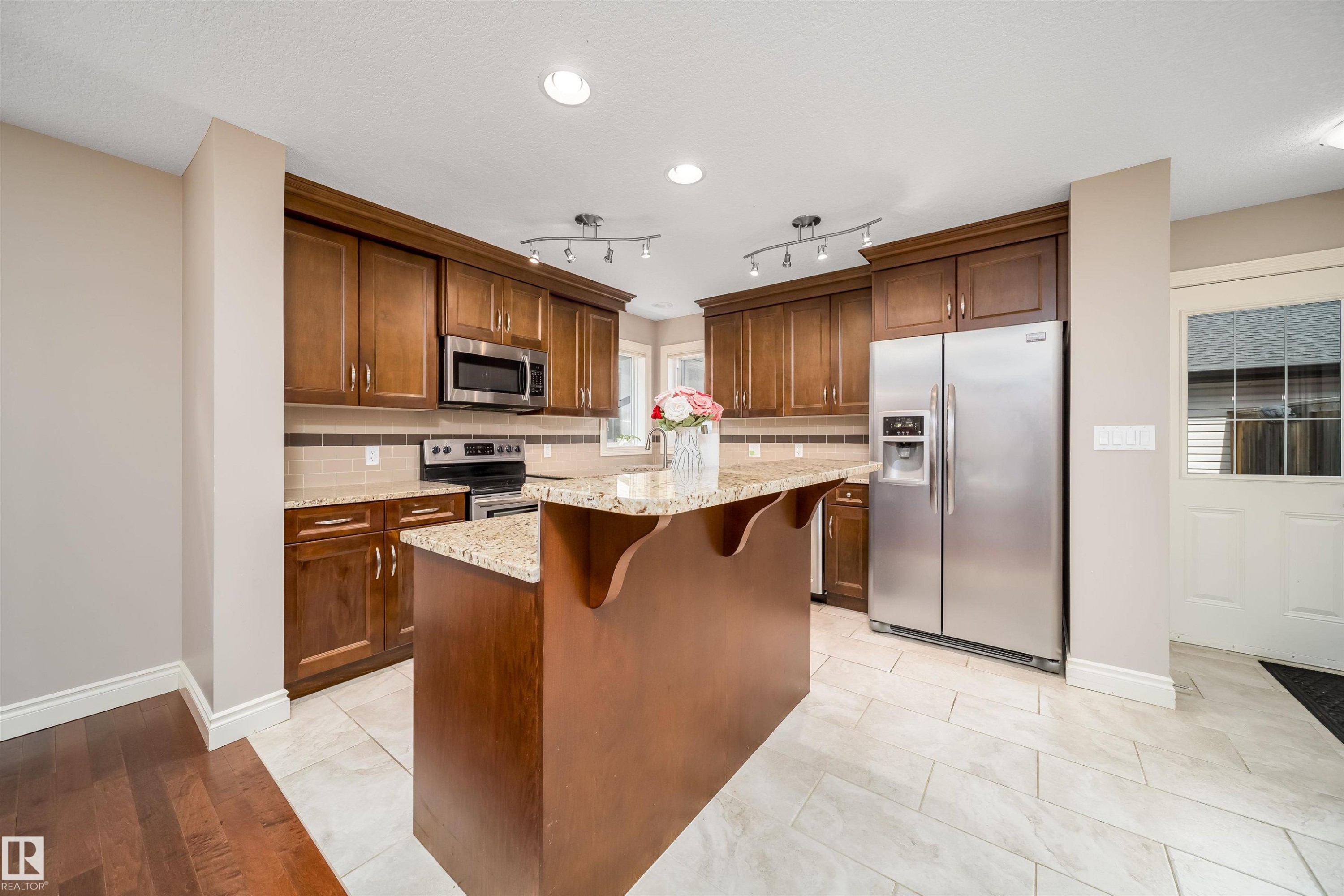 Kitchen featuring wood cabinetry, stainless steel appliances, a center island with a stone countertop, and recessed lighting - 11342 79 Avenue, Edmonton, AB - Indoor Photo Showing Kitchen With Stainless Steel Kitchen