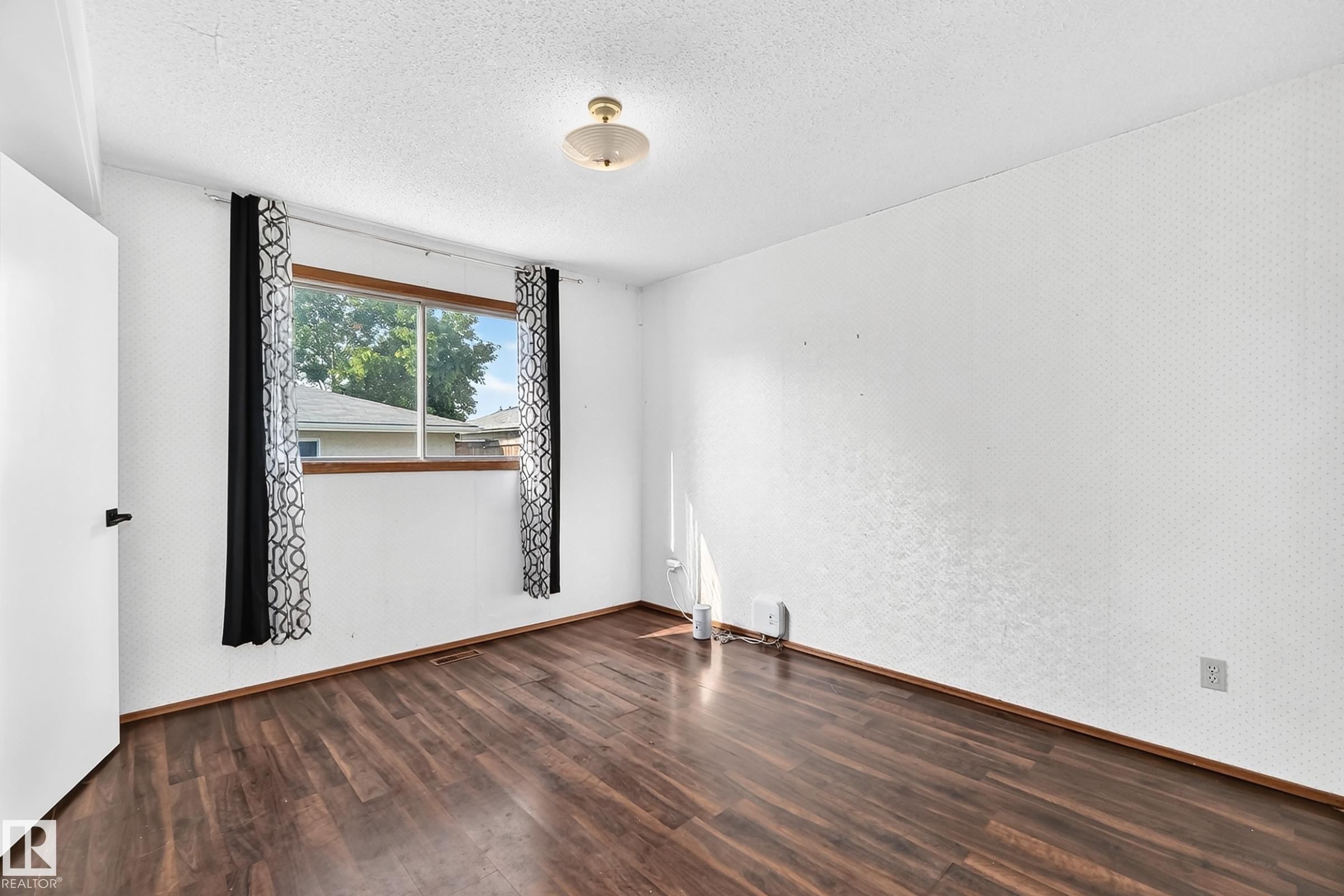 Room featuring wood-finish flooring, a double-paned window, and a flush-mount ceiling light fixture - 1928 68 Street Nw, Edmonton, AB - Indoor Photo Showing Other Room