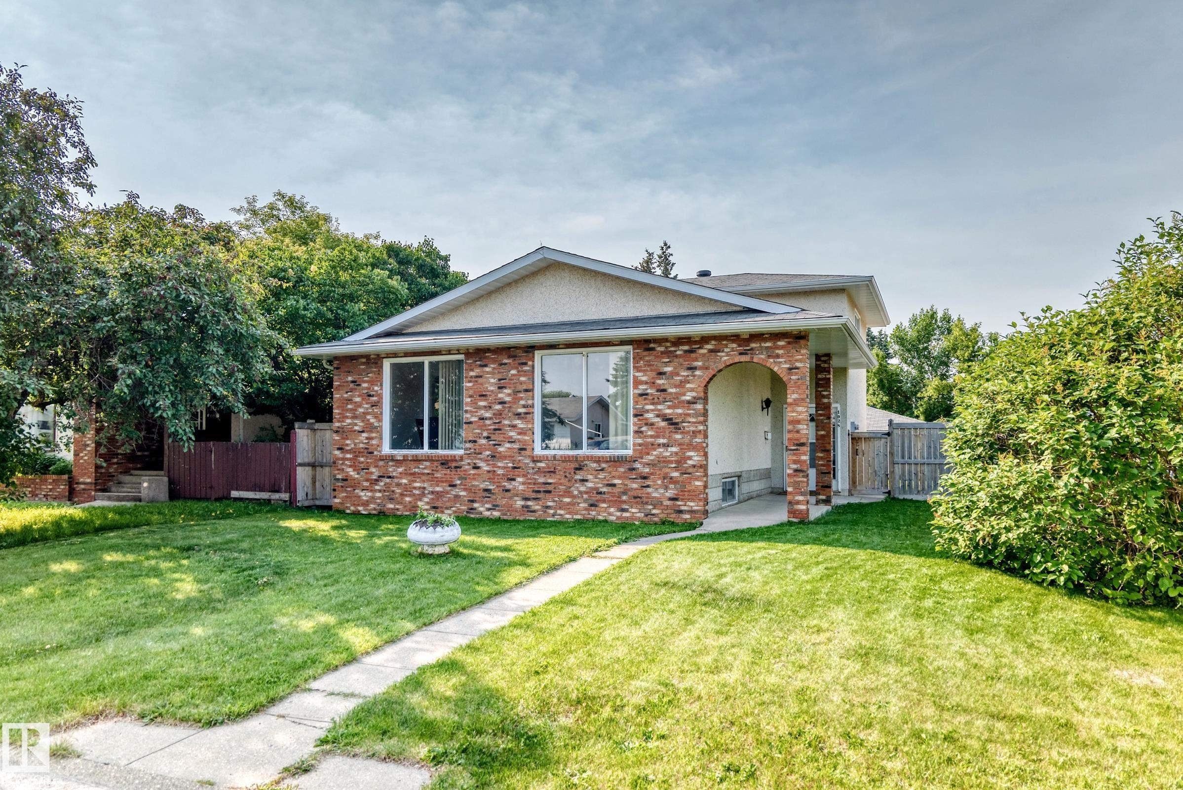 Brick-front exterior with an arched entryway, multiple windows, and a concrete pathway leading to the front door - 1928 68 Street Nw, Edmonton, AB - Outdoor