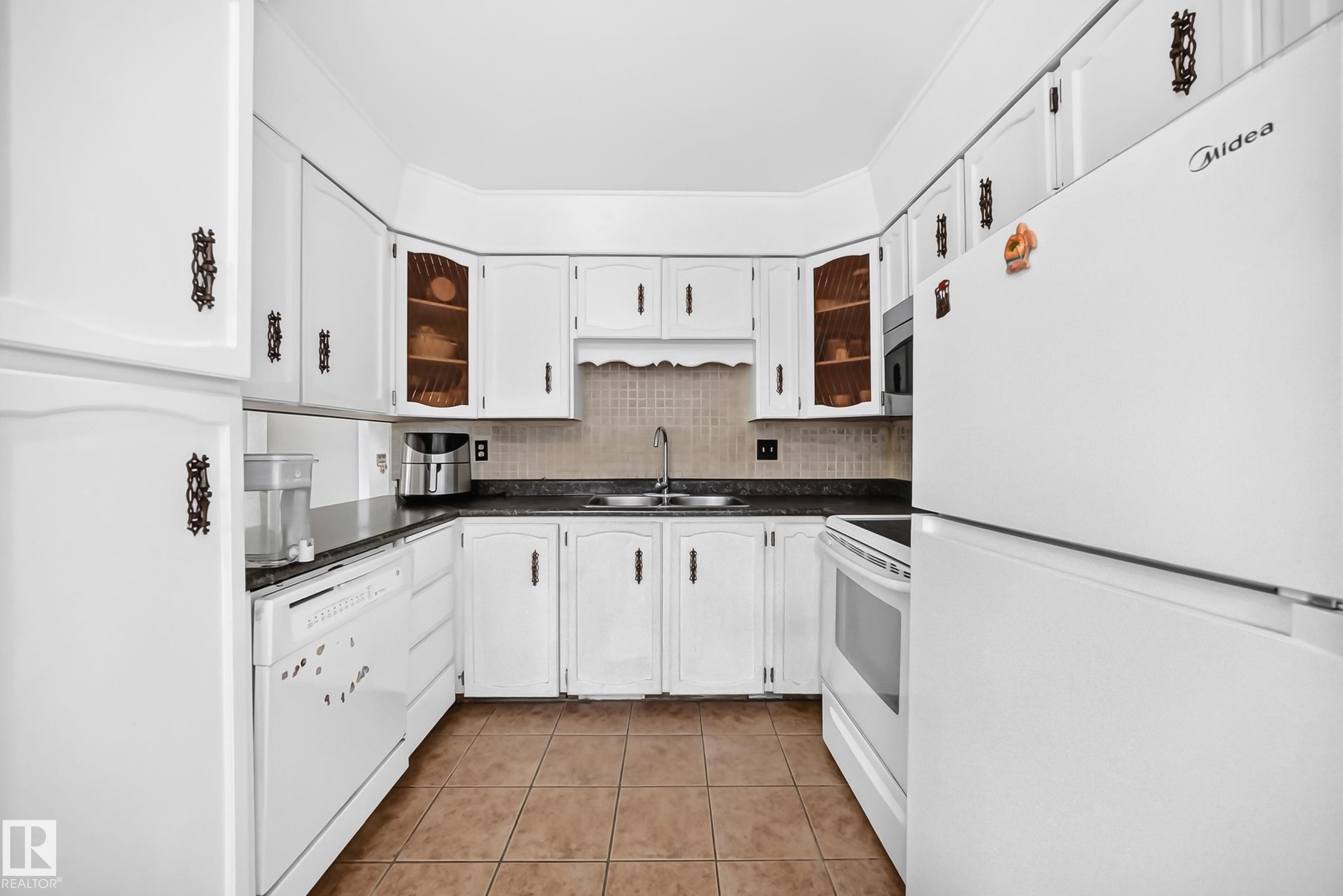 Kitchen featuring white cabinetry with dark hardware, dark countertops, and tile flooring - 1928 68 Street Nw, Edmonton, AB - Indoor Photo Showing Kitchen With Double Sink