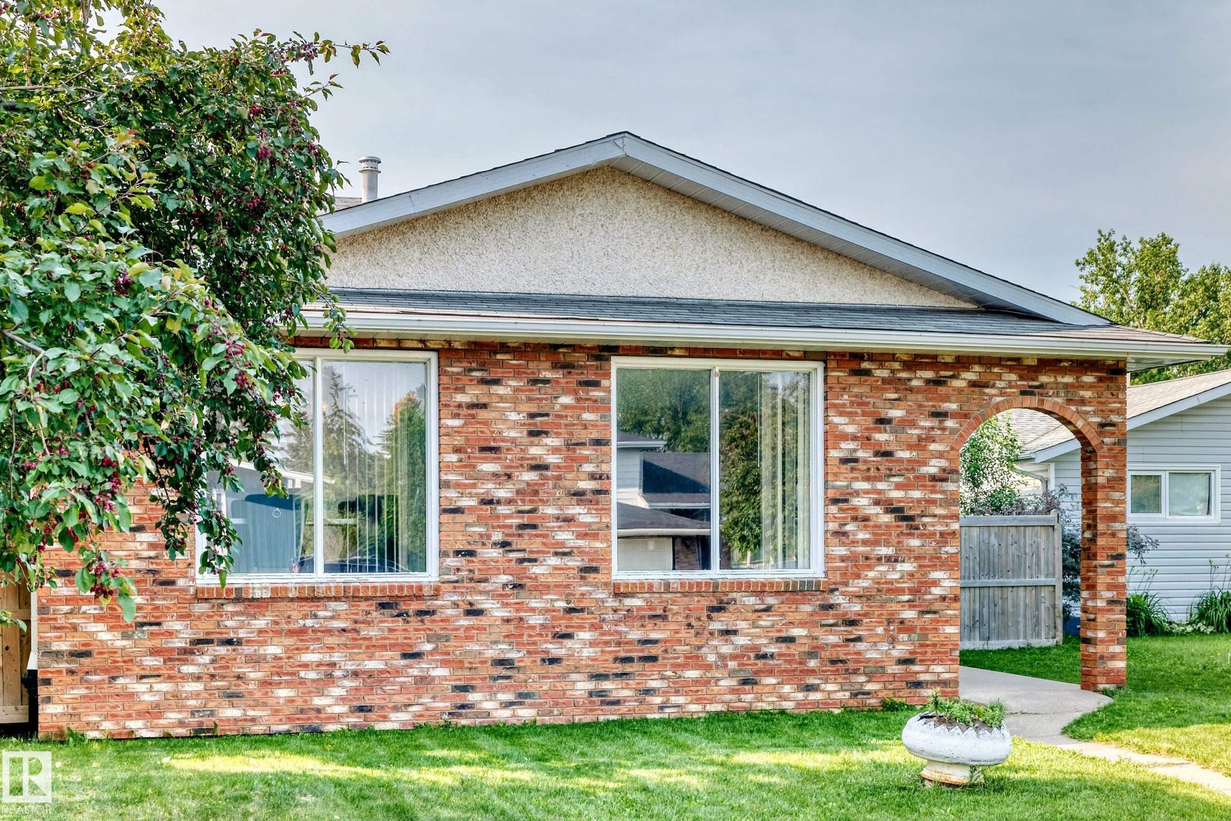 Brick exterior featuring two large windows and an arched entryway - 1928 68 Street Nw, Edmonton, AB - Outdoor