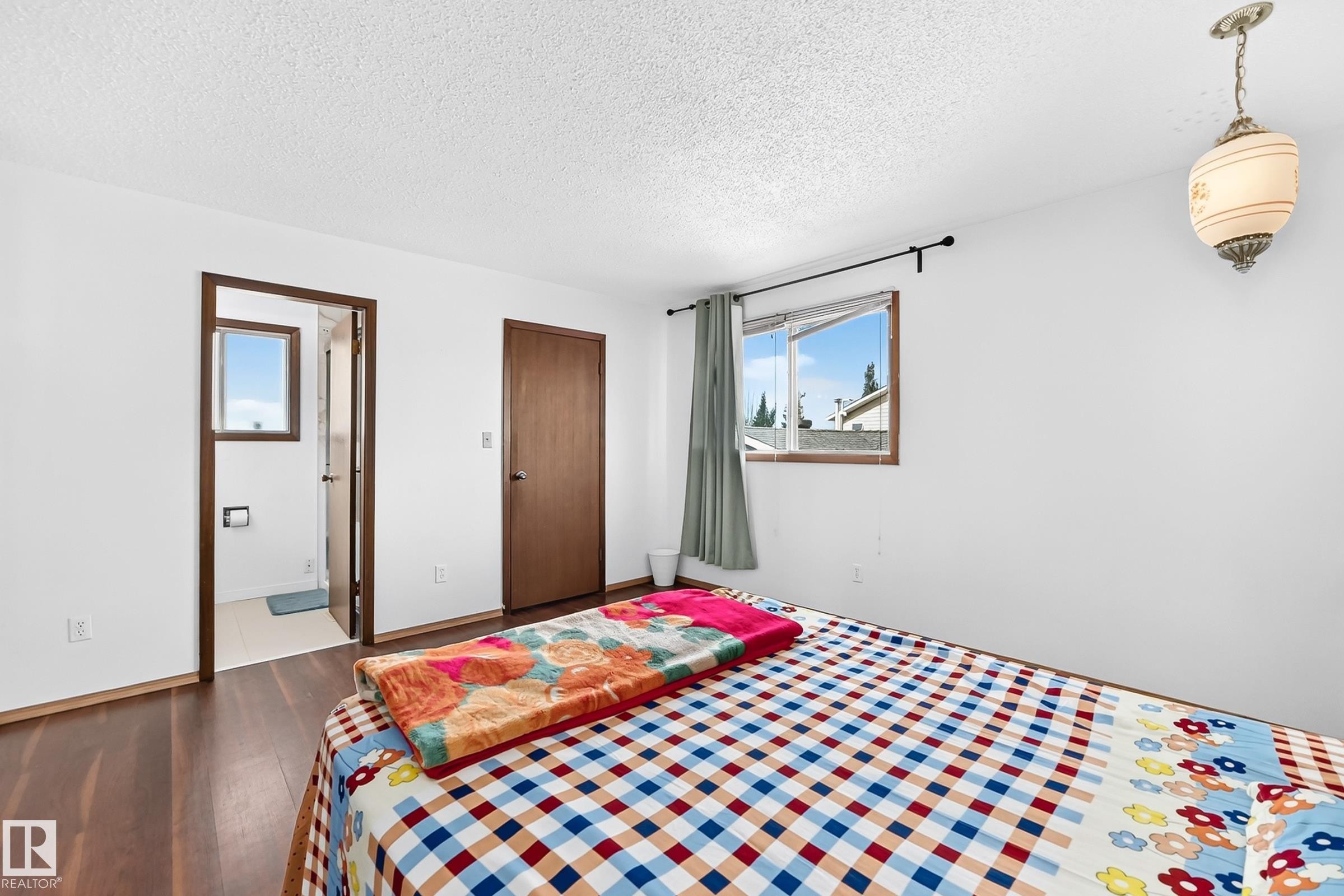 Interior room featuring wood-finish flooring, white walls, and a textured white ceiling - 1928 68 Street Nw, Edmonton, AB - Indoor Photo Showing Bedroom