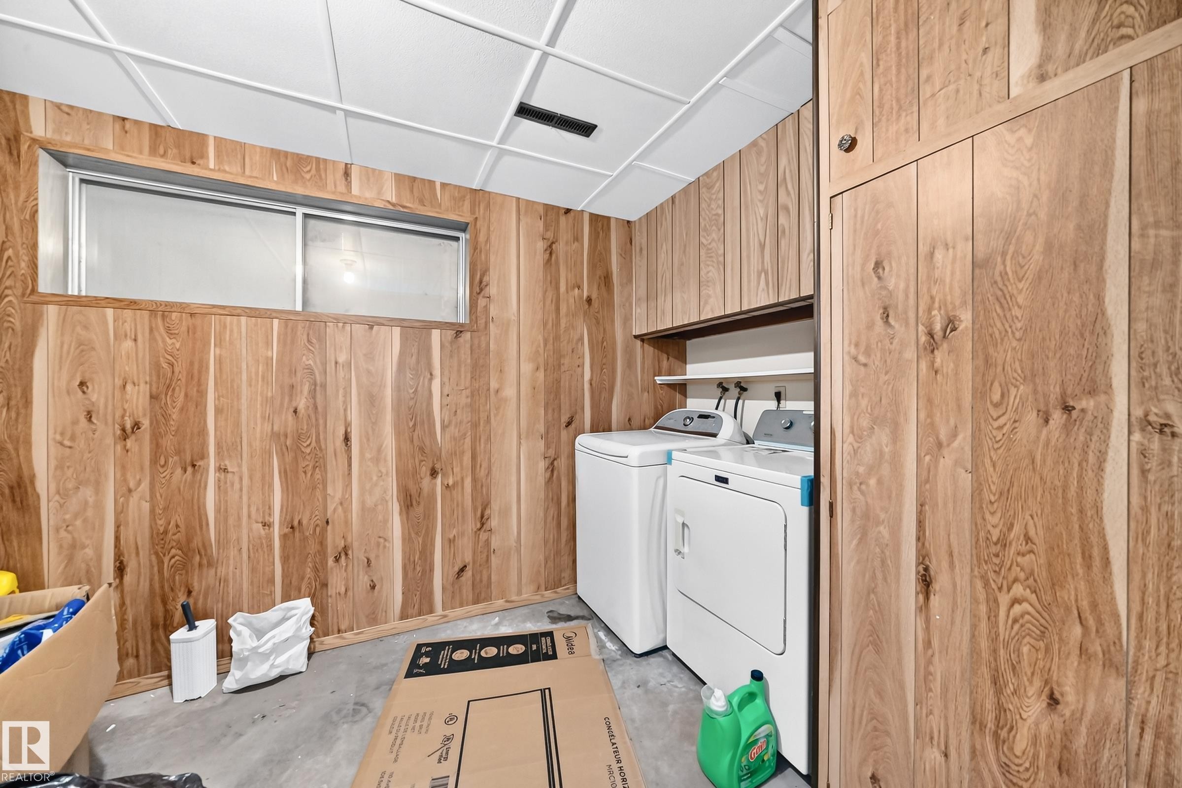Utility area featuring wood-finish paneling, concrete flooring, and a drop ceiling - 1928 68 Street Nw, Edmonton, AB - Indoor Photo Showing Laundry Room