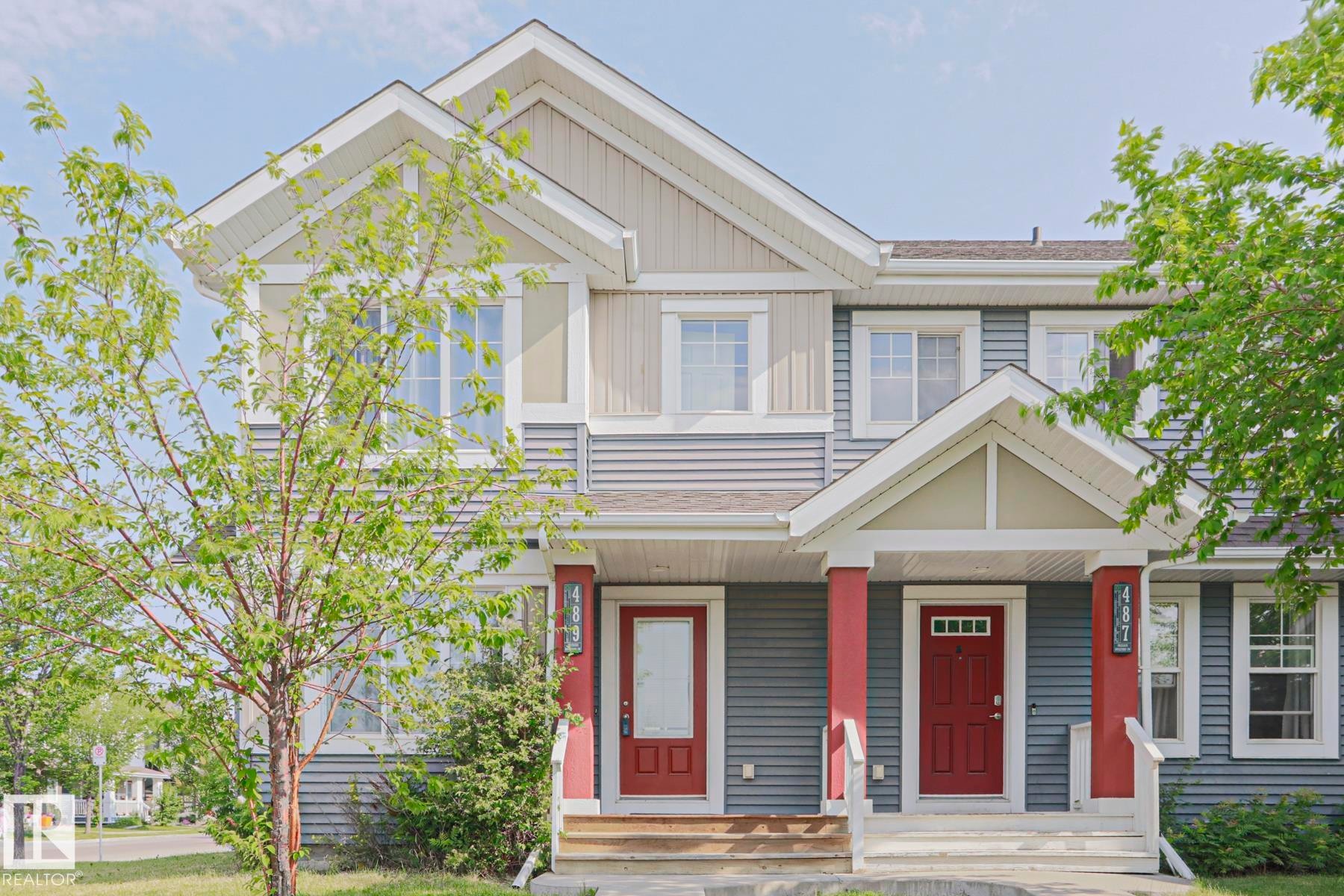 Two-story duplex with multi-tone siding, contrasting red doors, and white trim - 489 Orchards Boulevard Sw, Edmonton, AB - Outdoor With Facade