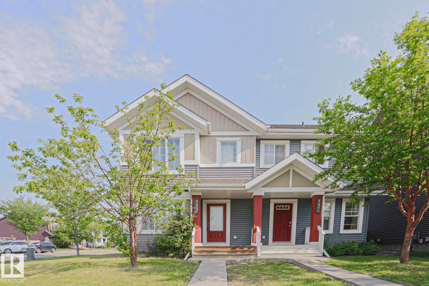 Two-story duplex featuring complementary siding, red entry doors, and white trim accents - 489 Orchards Boulevard Sw, Edmonton, AB - Outdoor With Facade