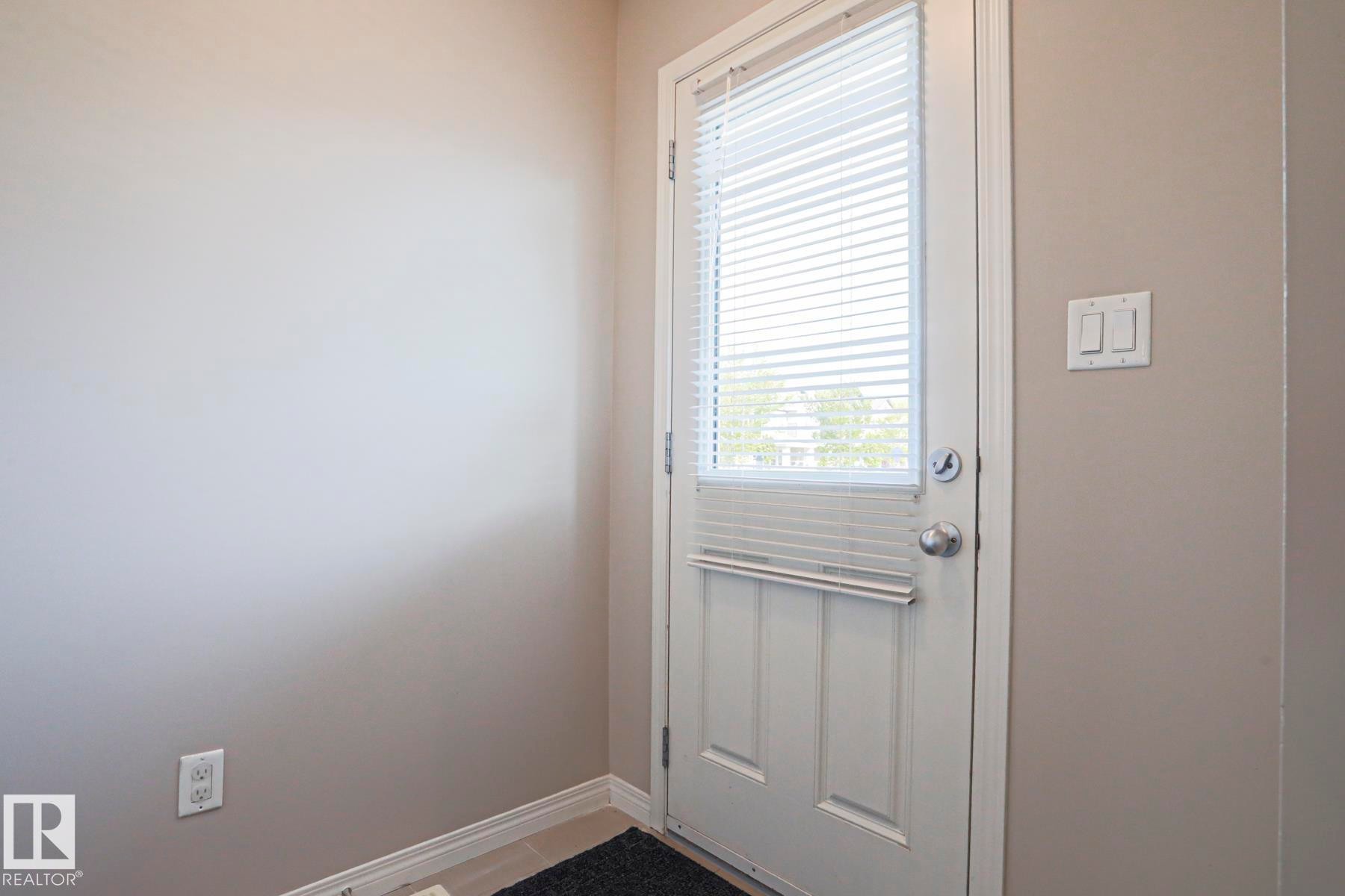 White paneled door with integrated blinds and brushed nickel hardware - 489 Orchards Boulevard Sw, Edmonton, AB - Indoor Photo Showing Other Room