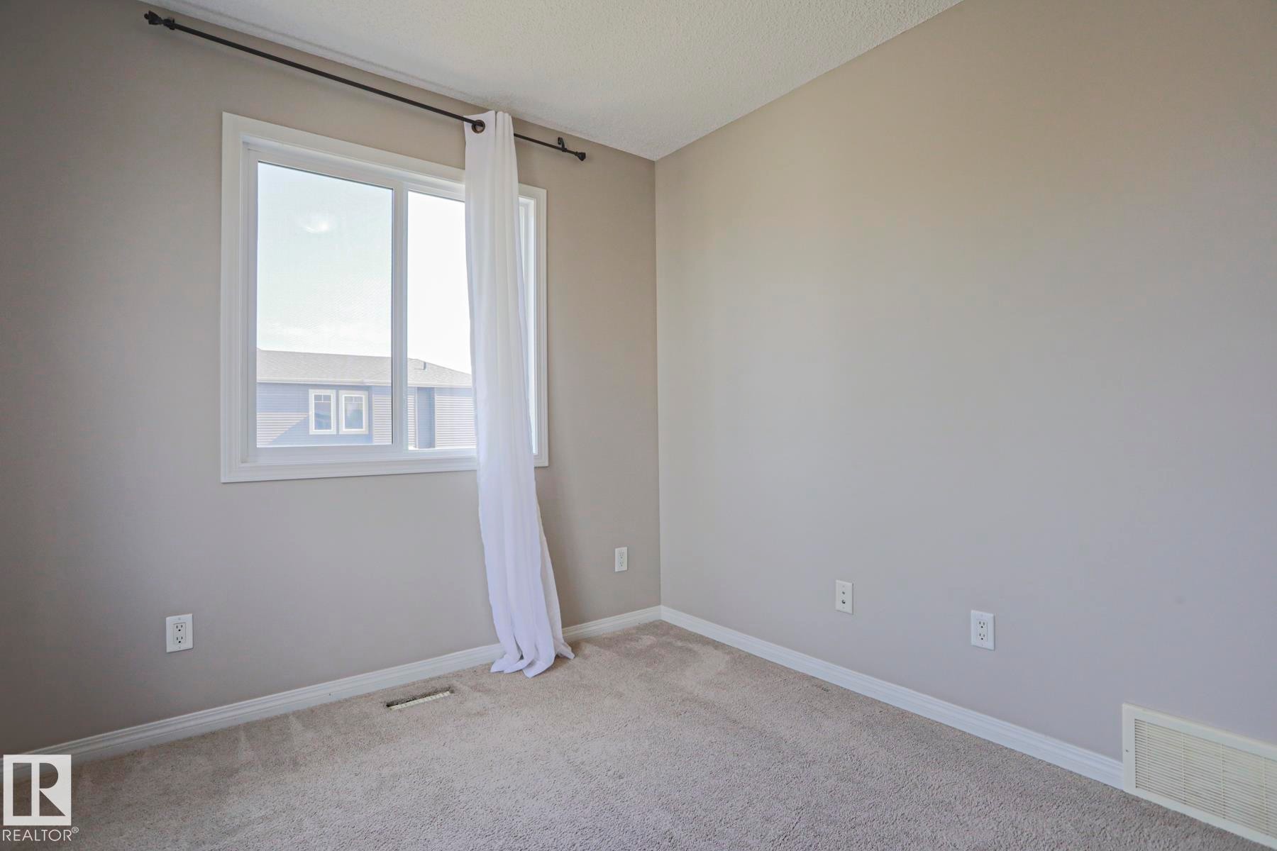Neutral tone wall paint with white trim, carpeting, and a window with white casing - 489 Orchards Boulevard Sw, Edmonton, AB - Indoor Photo Showing Other Room