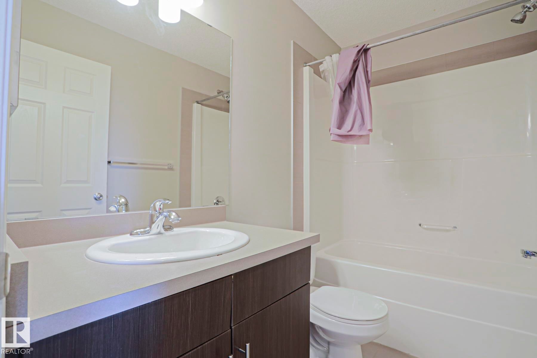 Bathroom featuring a white integrated sink, chrome faucet, and a wood-finish vanity with cabinet storage - 489 Orchards Boulevard Sw, Edmonton, AB - Indoor Photo Showing Bathroom