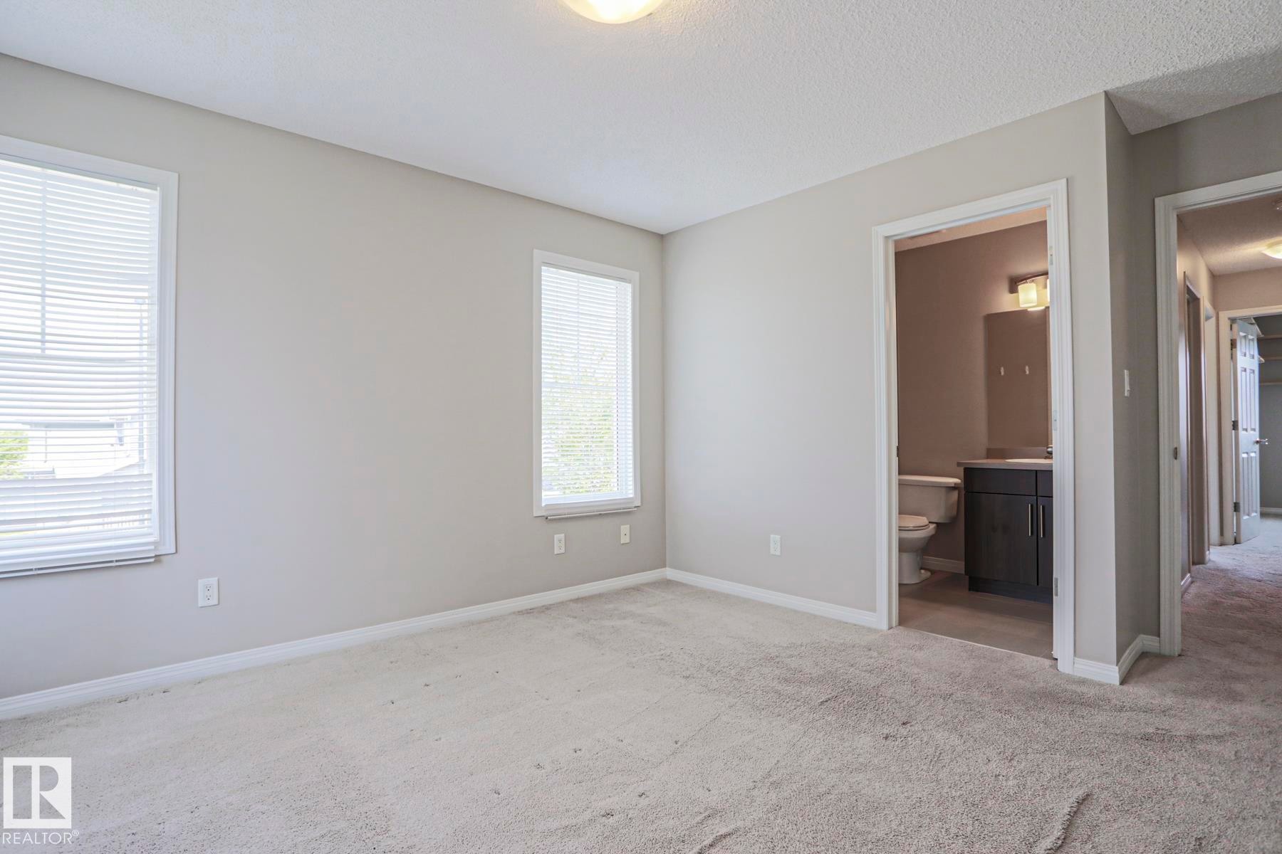 Carpeted room with two windows, a white ceiling, and light gray walls - 489 Orchards Boulevard Sw, Edmonton, AB - Indoor Photo Showing Other Room